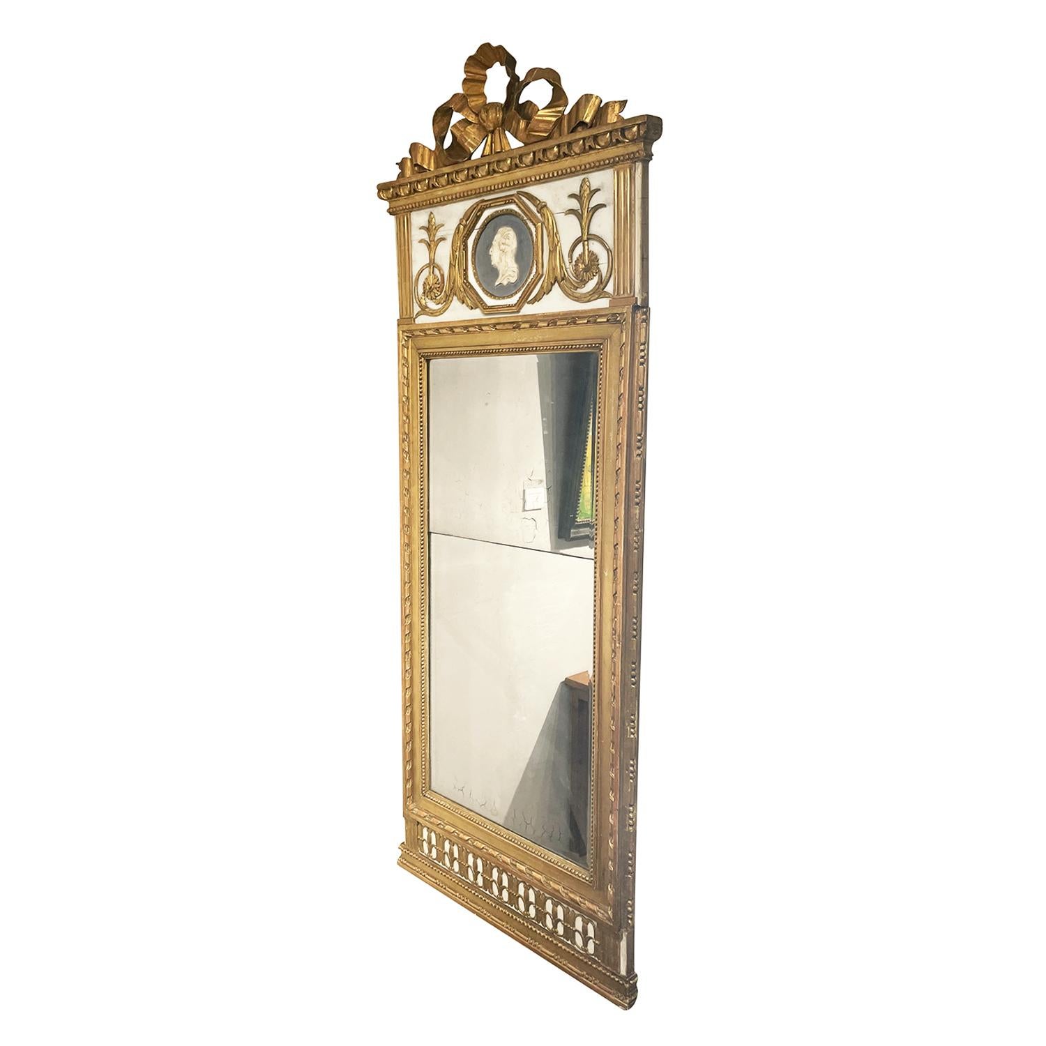 A gold, antique Swedish Gustavian wall mirror made of hand crafted gilded Pinewood with its original two-part mirrored glass, in good condition. The particularized carved Scandinavian wall décor piece is enhanced by detailed wood carvings and