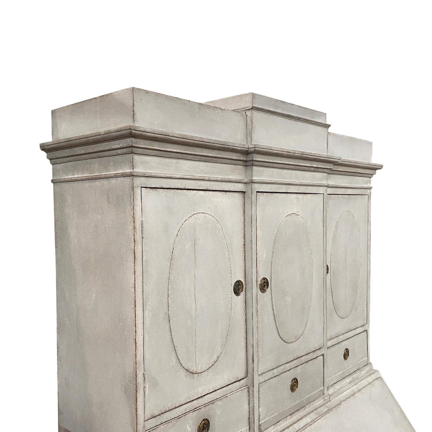 A 18th-19th century, light-grey, white antique Swedish Gustavian two part bureau made of hand crafted painted Pinewood, in good condition. The Scandinavian secretaire is composed with three upper doors and a writing flap, four large drawers and many