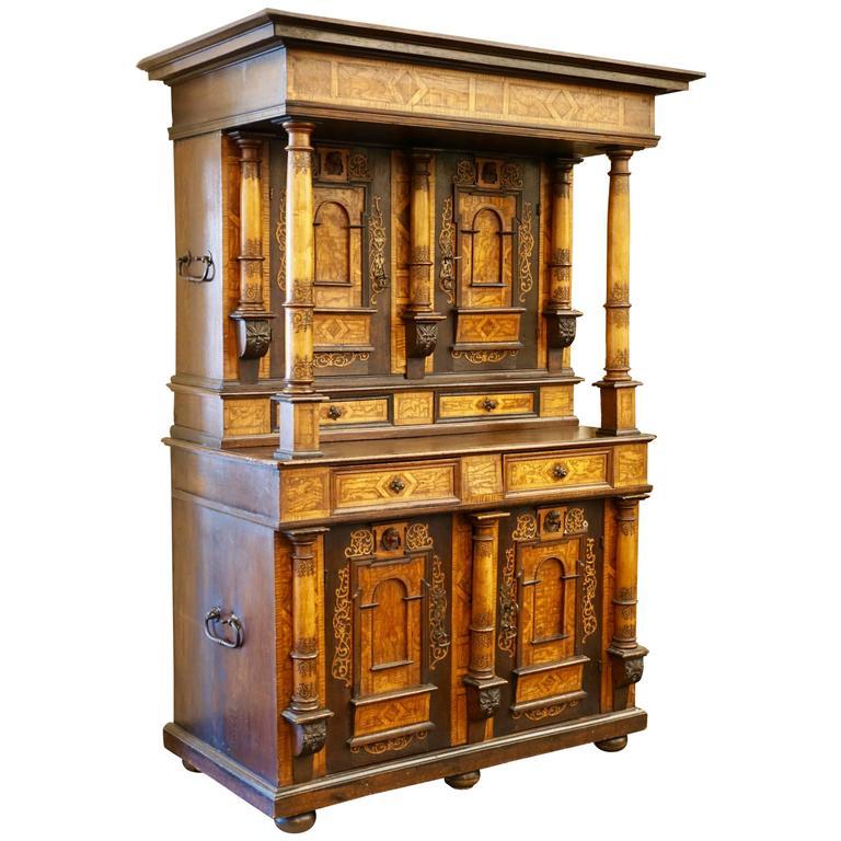 Rare 18th century Alsacienne inlaid cabinet, the stepped inlaid cornice on columnar supports over two doors with architectural panels surmounted by putti masks above similar two-door base, upper and lower sections revealing shelved interiors, raised