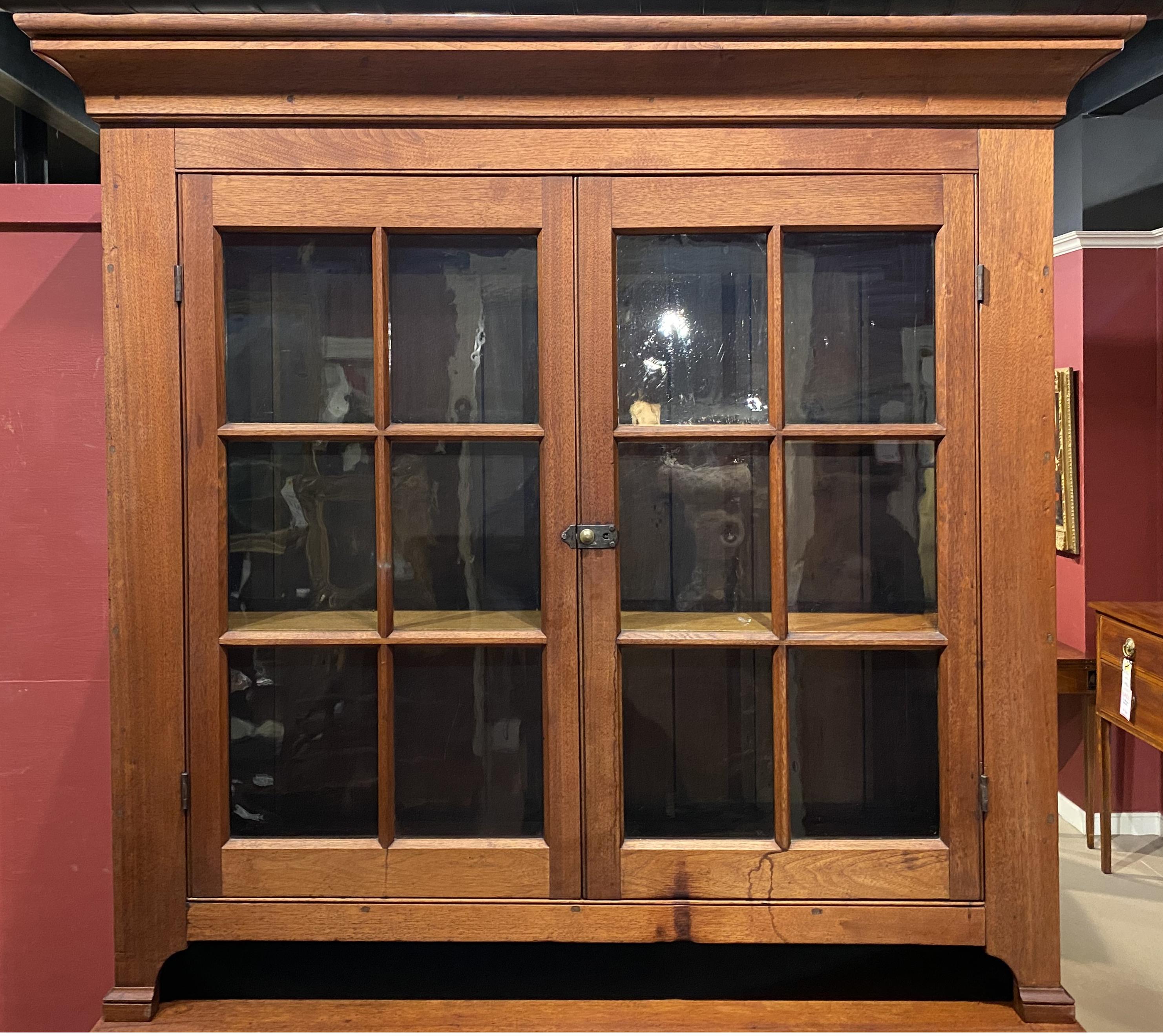 A fine example of a 18th/19th century walnut two part stepback cupboard, its upper case with a molded cornice surmounting two doors with original glass panels, opening to two interior shelves and tongue & groove back, over a lower case with work