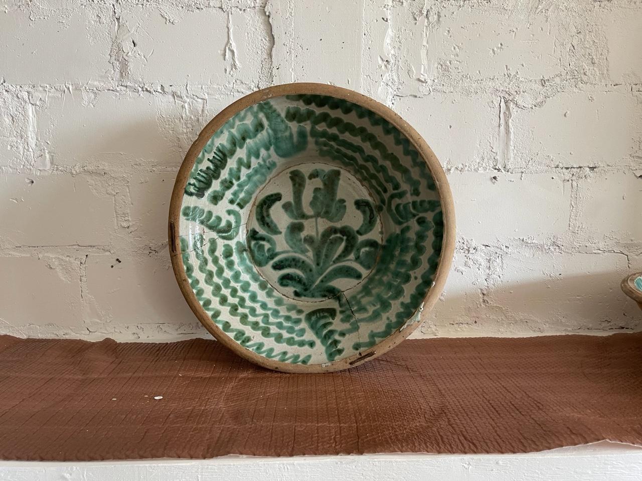 A very large antique Spanish Lebrillo bowl in earthenware, made of hand crafted terra cotta, originating from Granada, Spain. Featuring a glaze decoration in the typical Morisco green over a milk-white glaze. A painted flower motif is painted onto