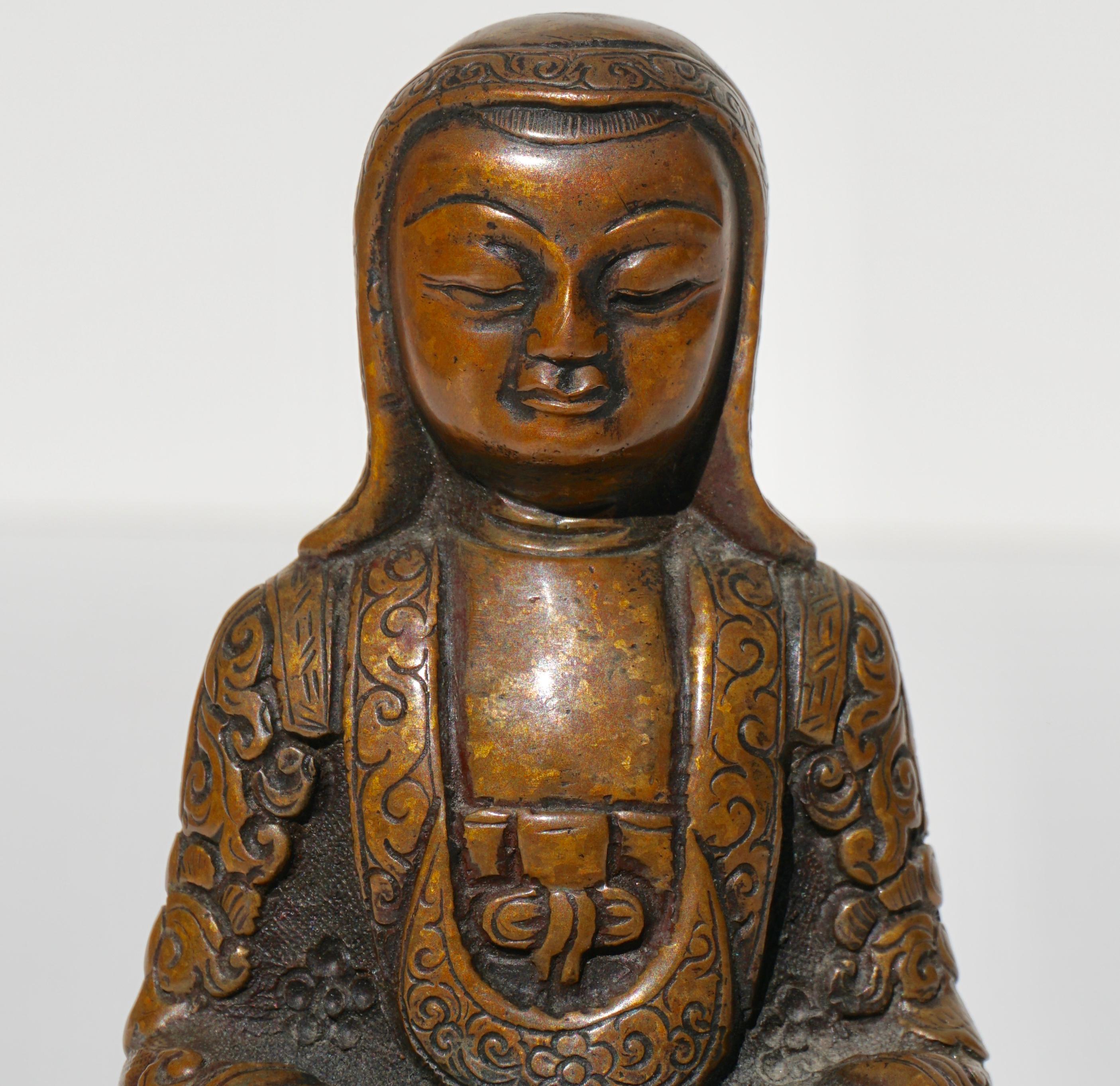 A peaceful Monk or Lama seated in a Buddhist crossed legged posture on a lotus throne (Padmasana) with both hands in a meditation gesture of Dhyana Mudra. His patched garments and bonnet are incised in a skilful manner typical of the Tsang atelier.