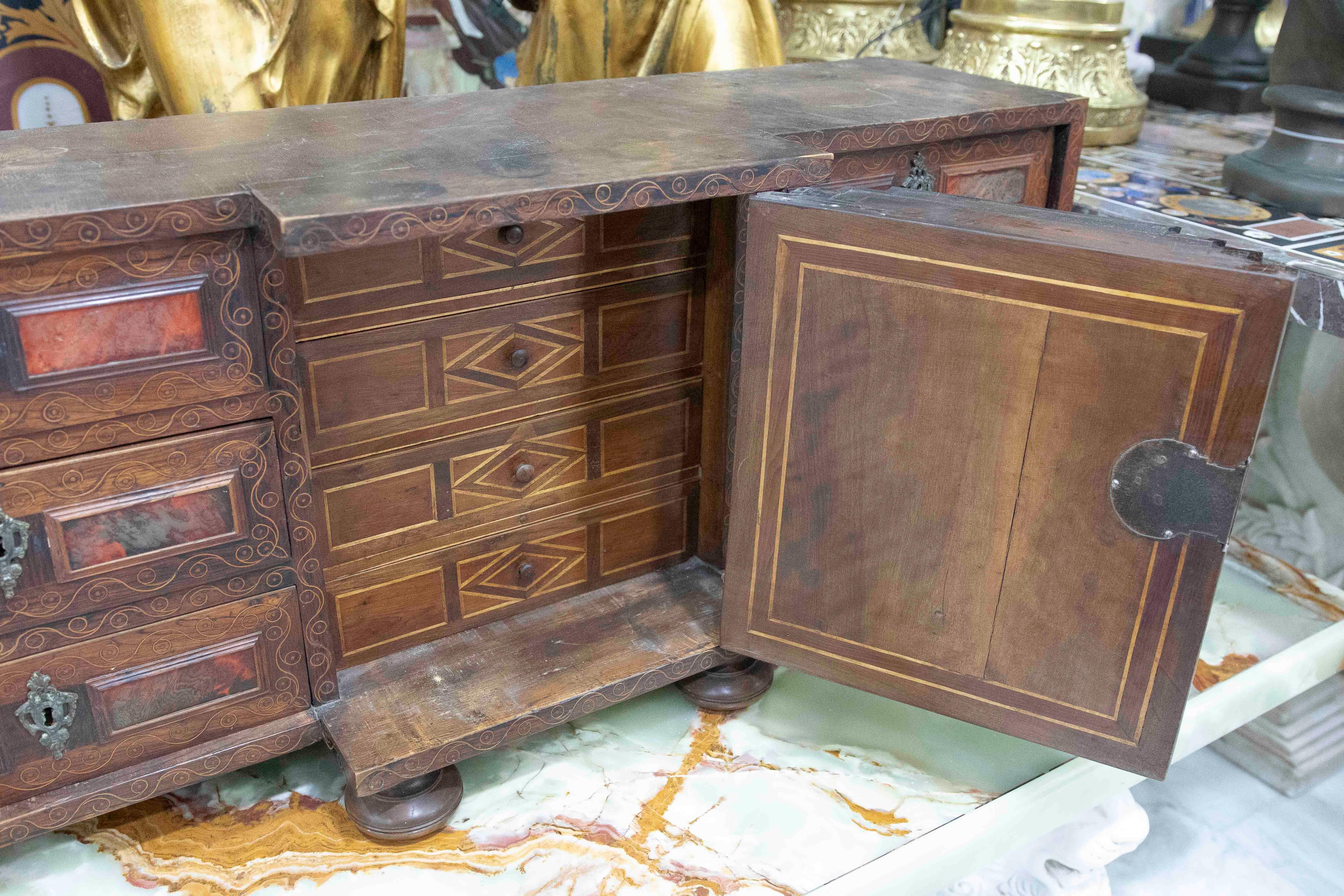 Exceptional 18th-century Spanish chest of drawers, crafted in wood with marquetry and inlay details in reddish and dark tones. It features multiple drawers with original wrought iron fittings and a central chapel shaped like a small altarpiece,