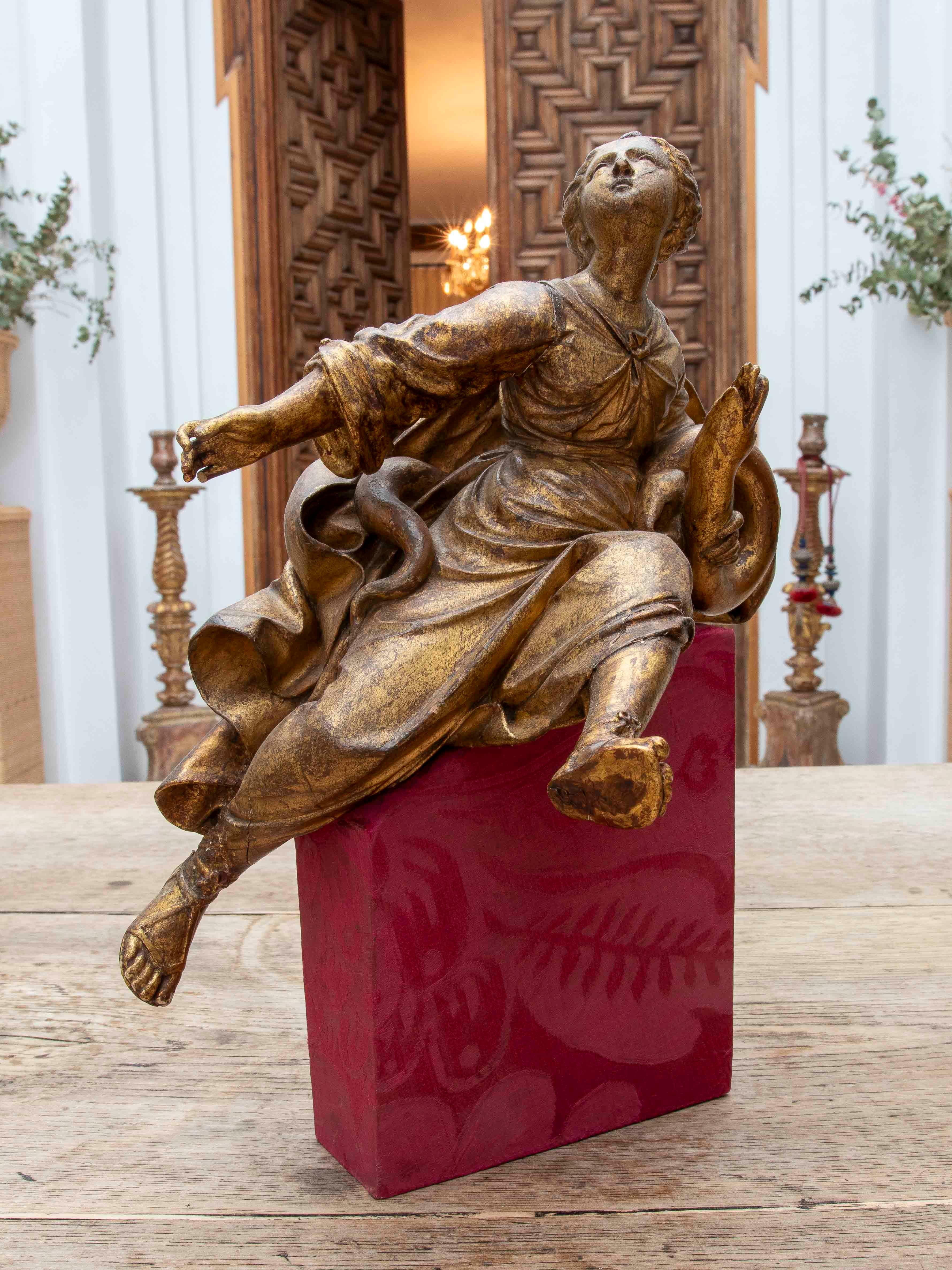 A refined Baroque sculpture carved in wood and gilded with gold leaf, depicting an allegorical female figure in an upward movement. The work, likely part of a sculptural group for an altarpiece or sacred architectural decoration, stands out for its