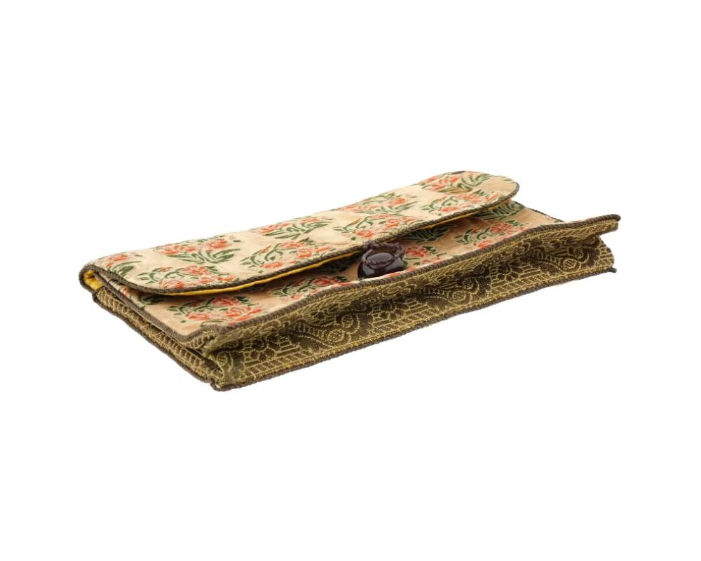 An antique Persian Iranian Safavid hand woven textile hand bag, circa 18th century. The outer fabric is adorned with intricate floral motifs, featuring red and green patterns. The interior is lined with a bright yellow satin material, giving the