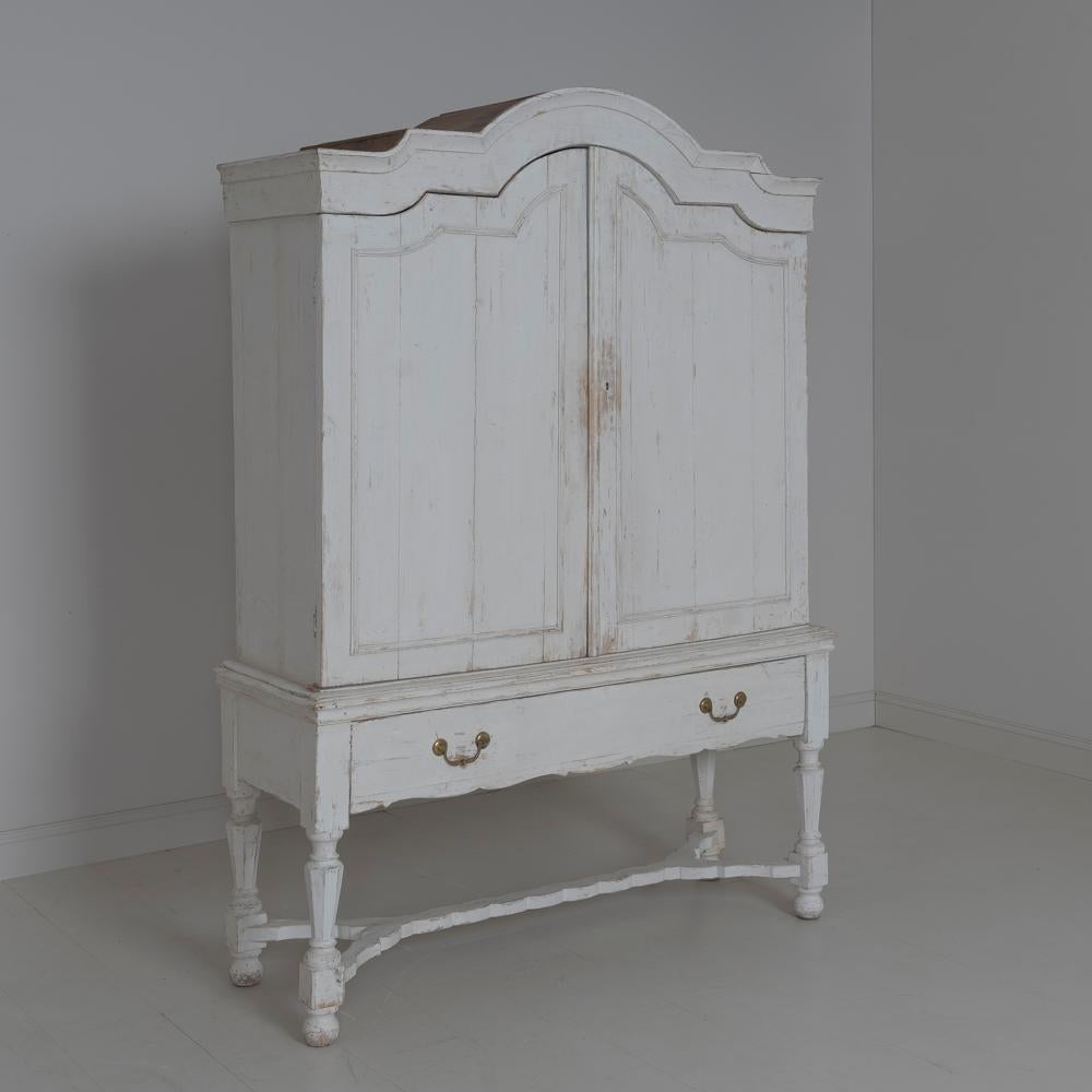 A stunning, two-part late 18th c. cabinet from northern Belgium wearing old paint. Original hardware with later lock and key. Beautifully scalloped cornice with scalloped detail on the drawer and stretcher base. There is plenty of storage in the