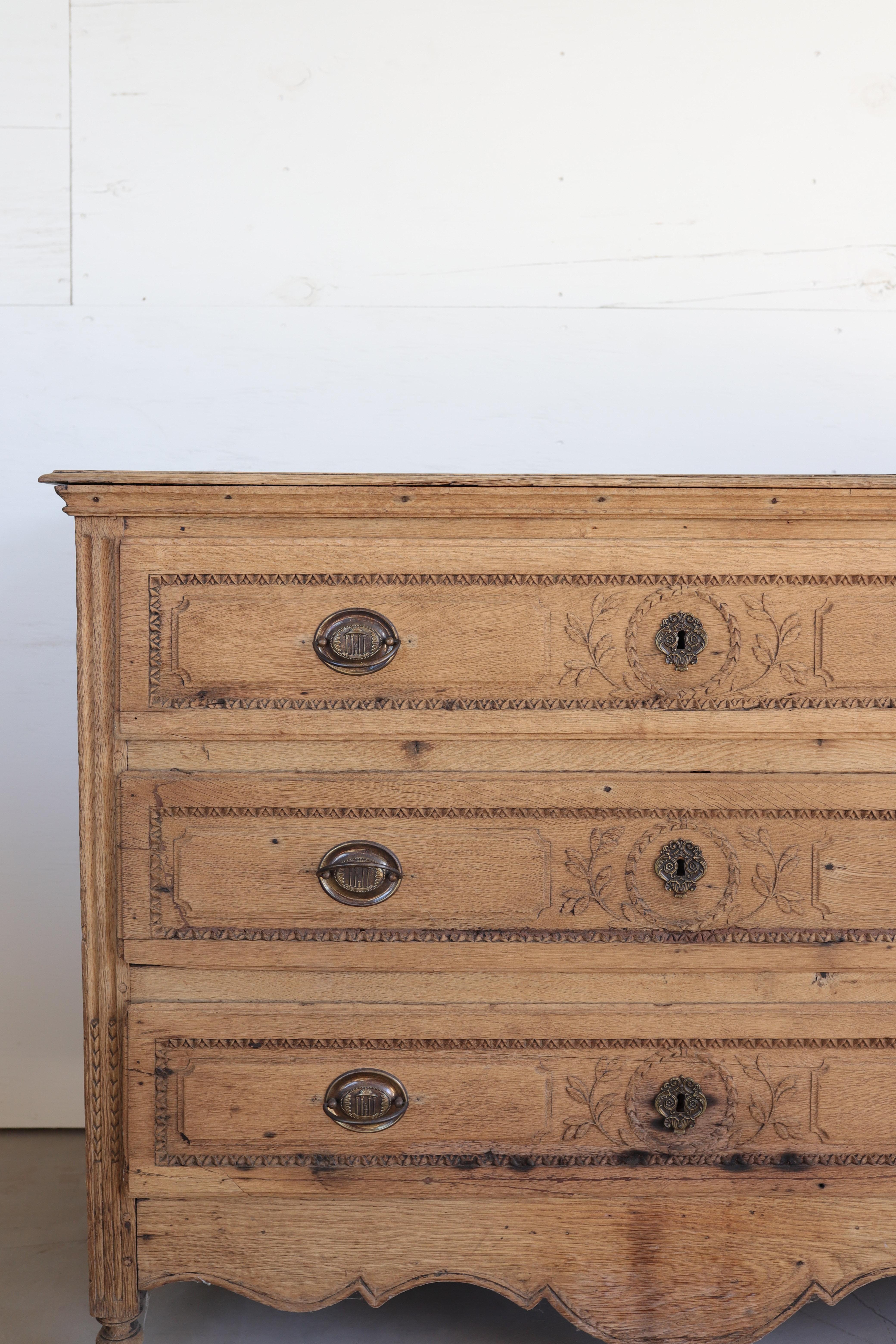 Une exquise commode belge du XVIIIe siècle fabriquée en chêne massif, magnifiquement blanchie pour révéler la chaleur naturelle et le caractère du grain du bois. La façade présente des détails néoclassiques finement sculptés à la main - de délicats
