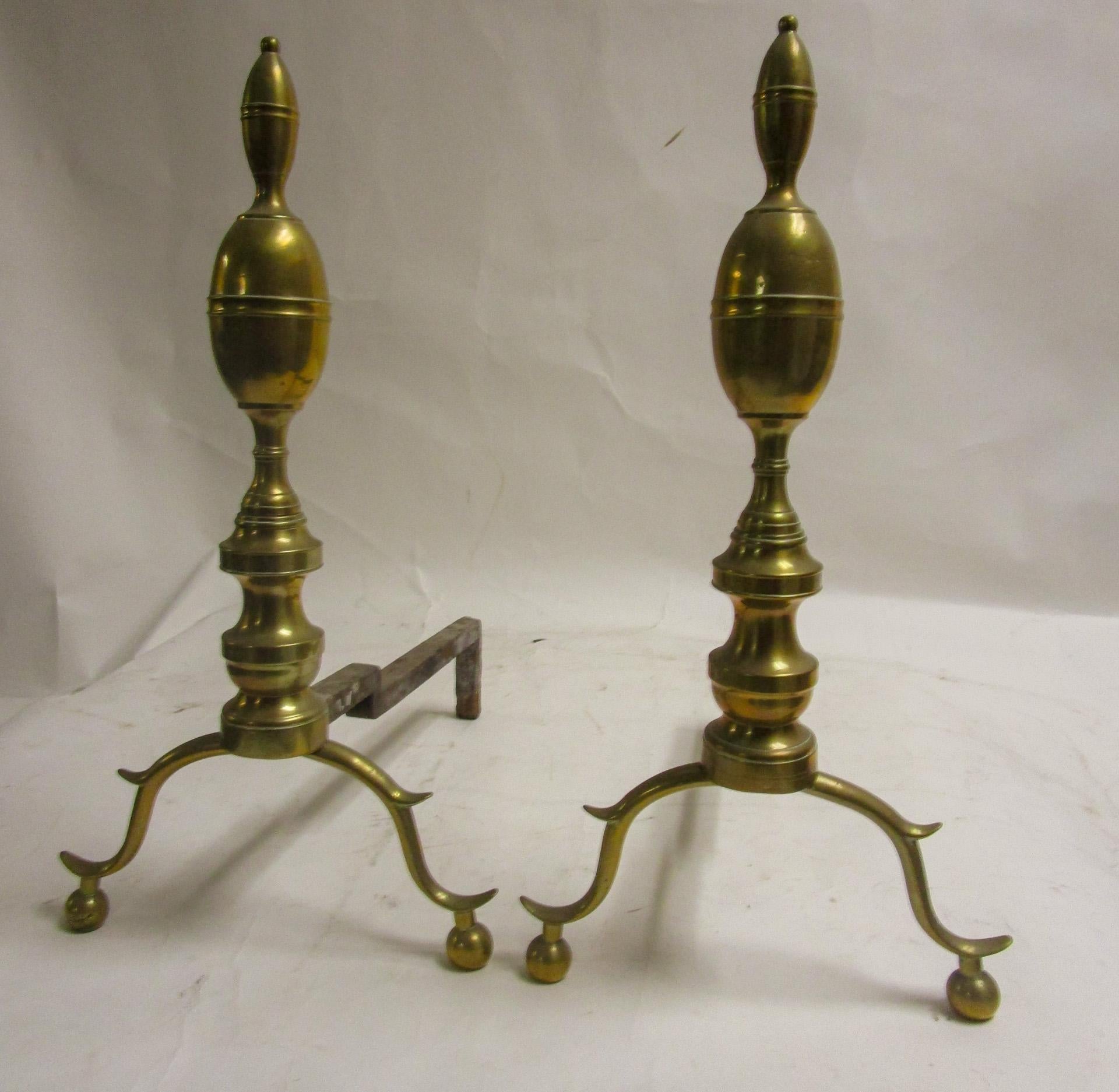 This graceful pair of American brass andiron/ firedogs feature smaller belted 
