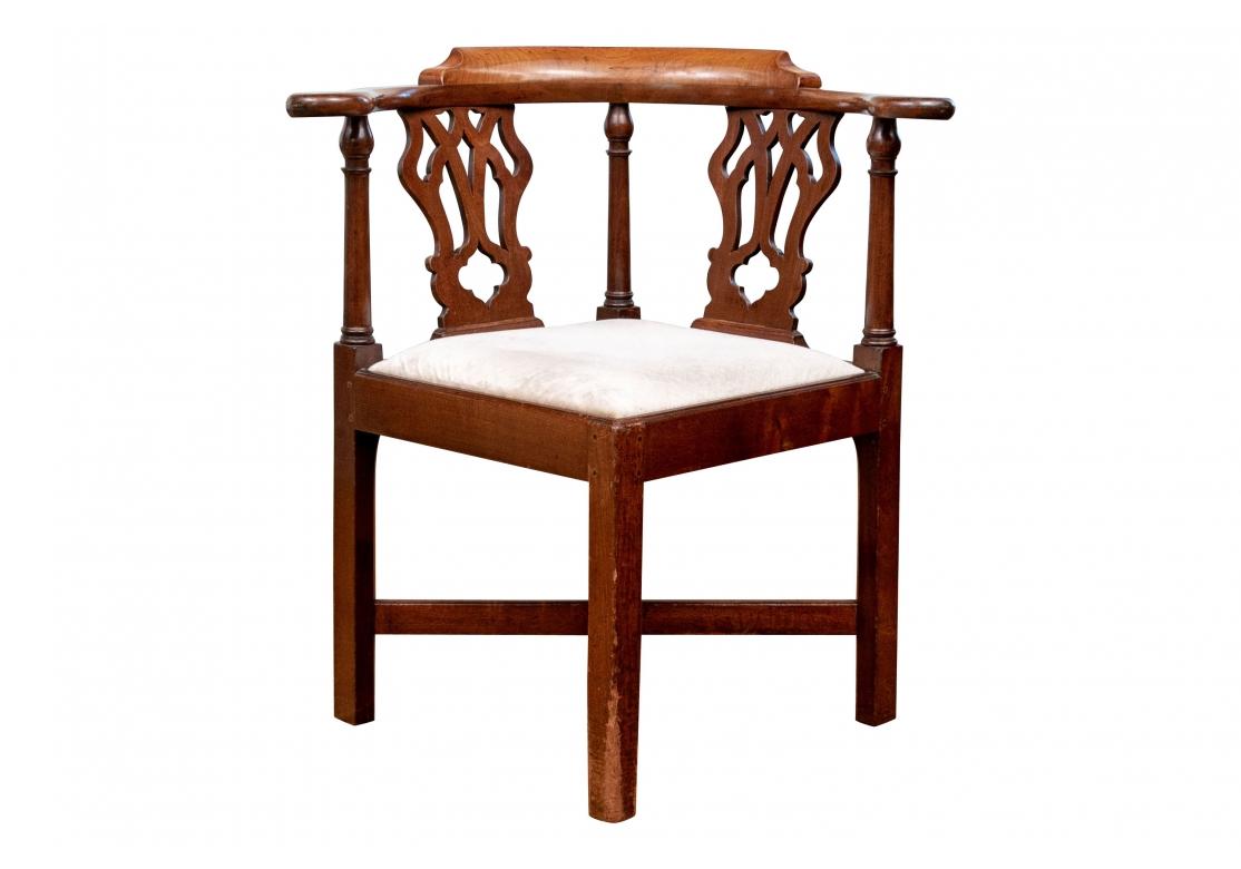 Finely crafted with a tub shaped back with a carved, curved and raised crest rail and scrolled arm ends. Openwork vasiform splats on the sides and turned arm supports. Raised on square legs with a flat X stretcher. Along with a slip seat upholstered