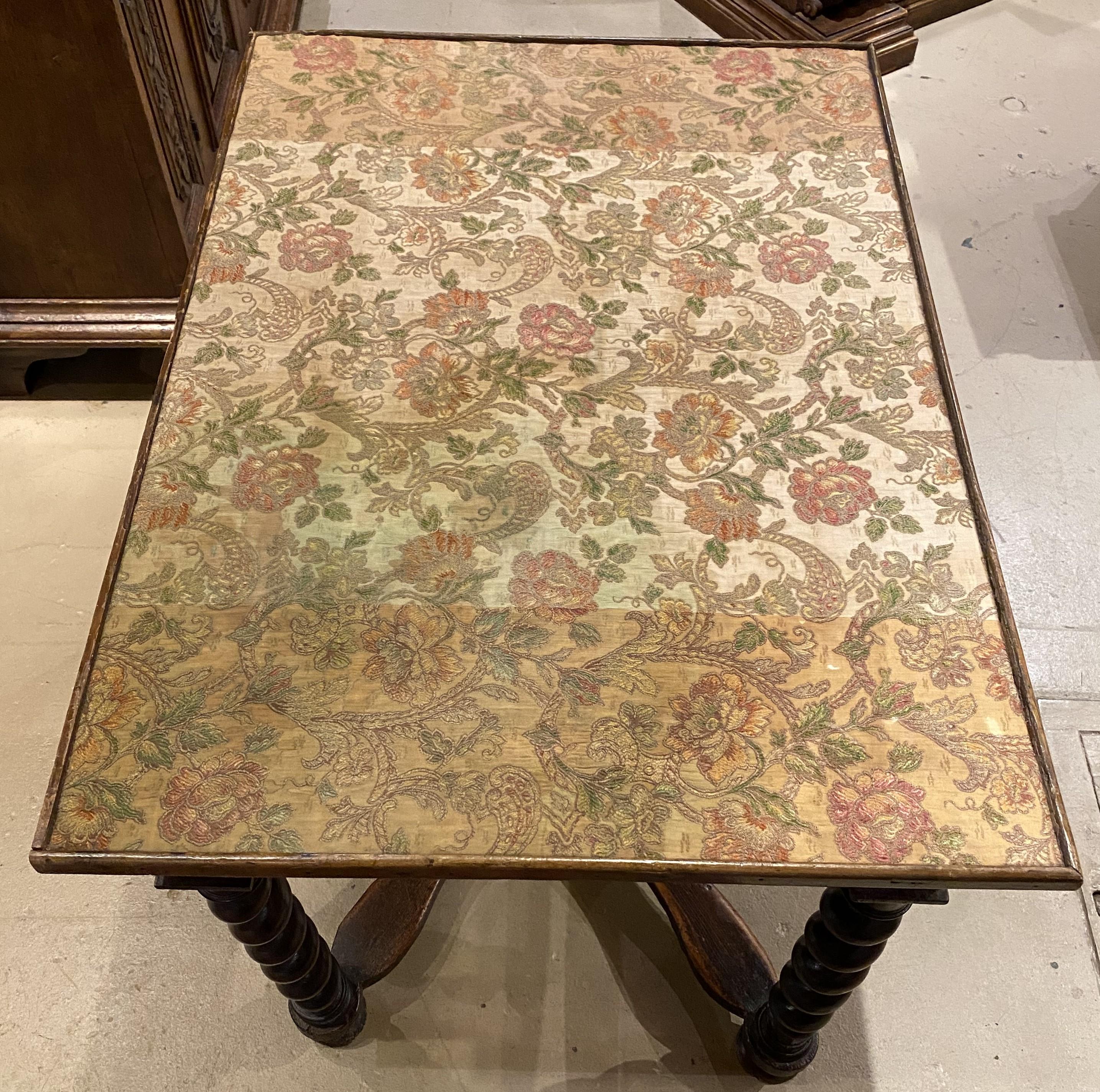 A fine example of a Continental fruitwood rectangular table with foliate needlework fabric lined top with wooden border, a scrollwork inlaid frieze drawer, additional foliate carved frieze decoration, supported by four barley twist carved legs and