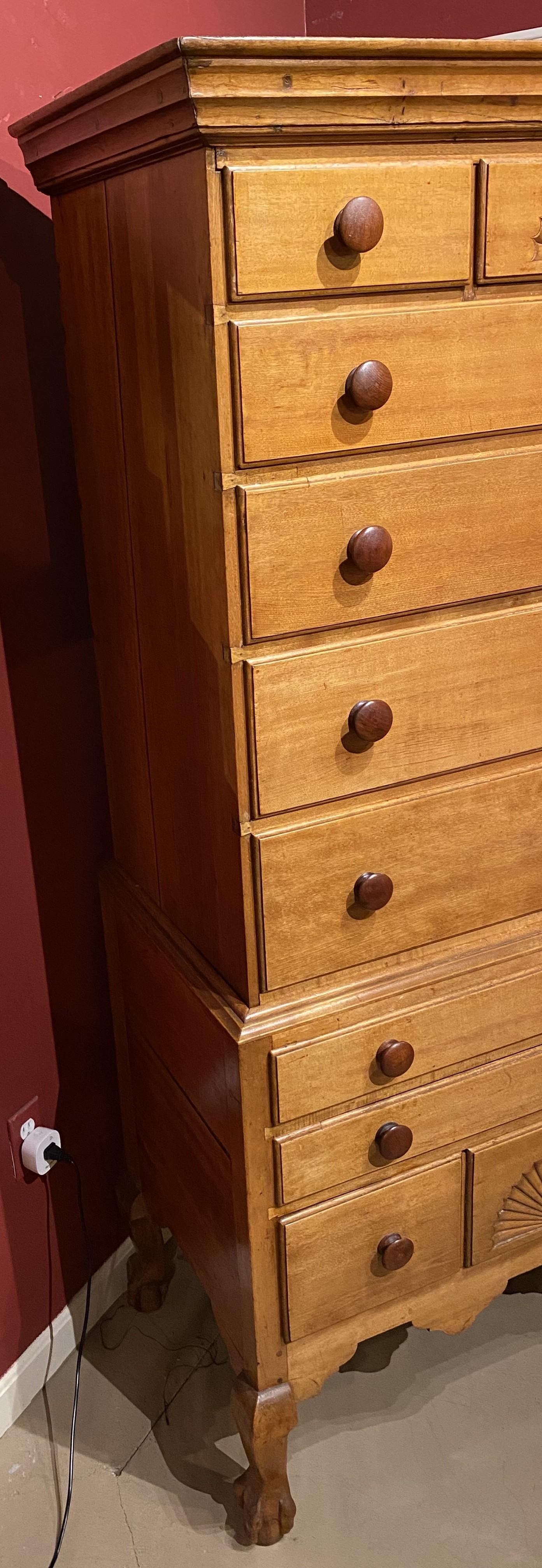 A fine 18th century Dunlap School two part highboy in birch, with molded cornice surmounting an upper case with three fitted drawers, a central drawer with a carved radial fan decoration, over four graduated drawers, over a lower case with three
