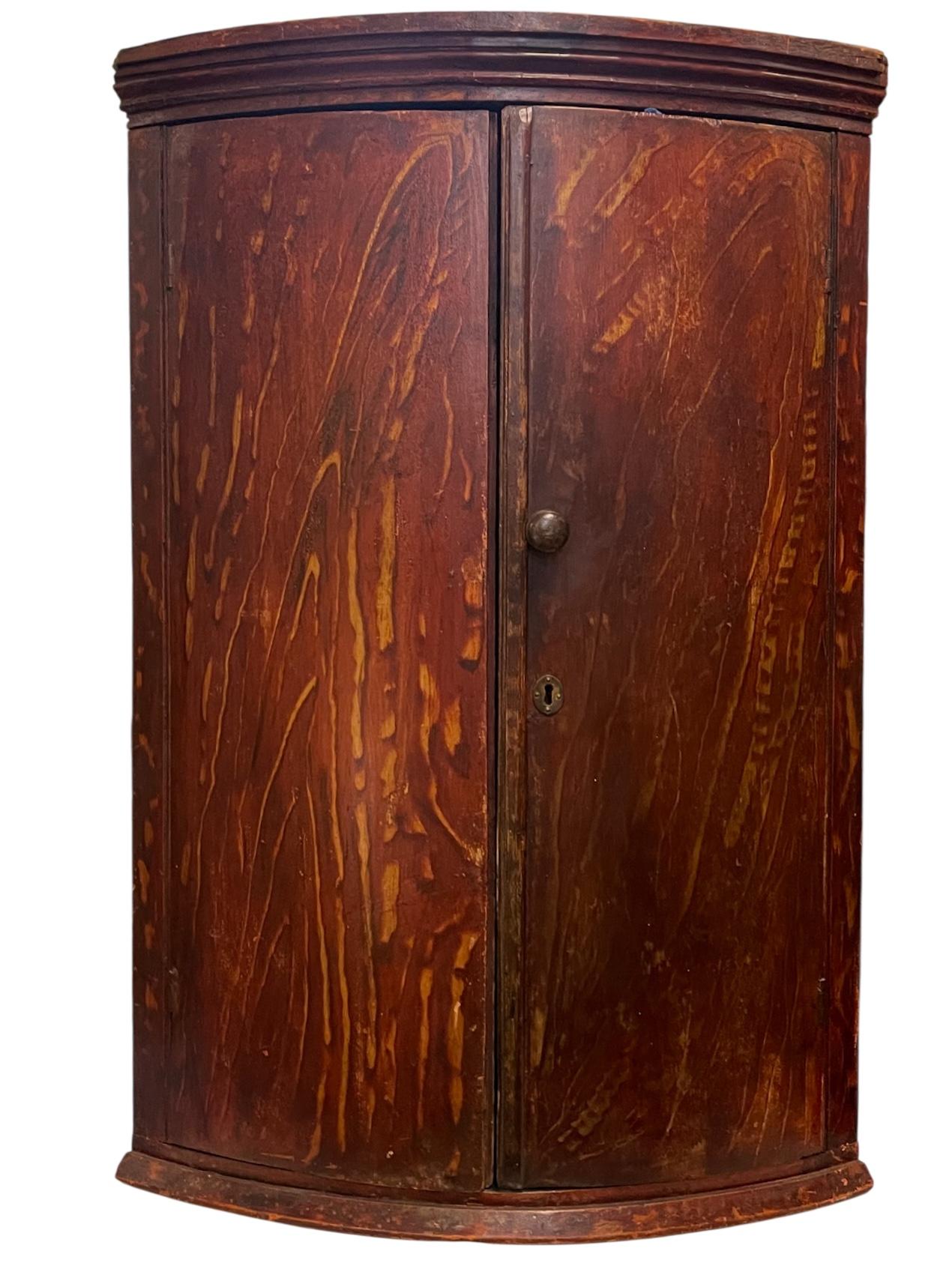This is an excellent example of a 18th century grain painted corner cabinet. I love the finish and the surprise of opening to a pop of blue. It is in very good antique condition. When you examine the measurements, you can visualize a rounded pie