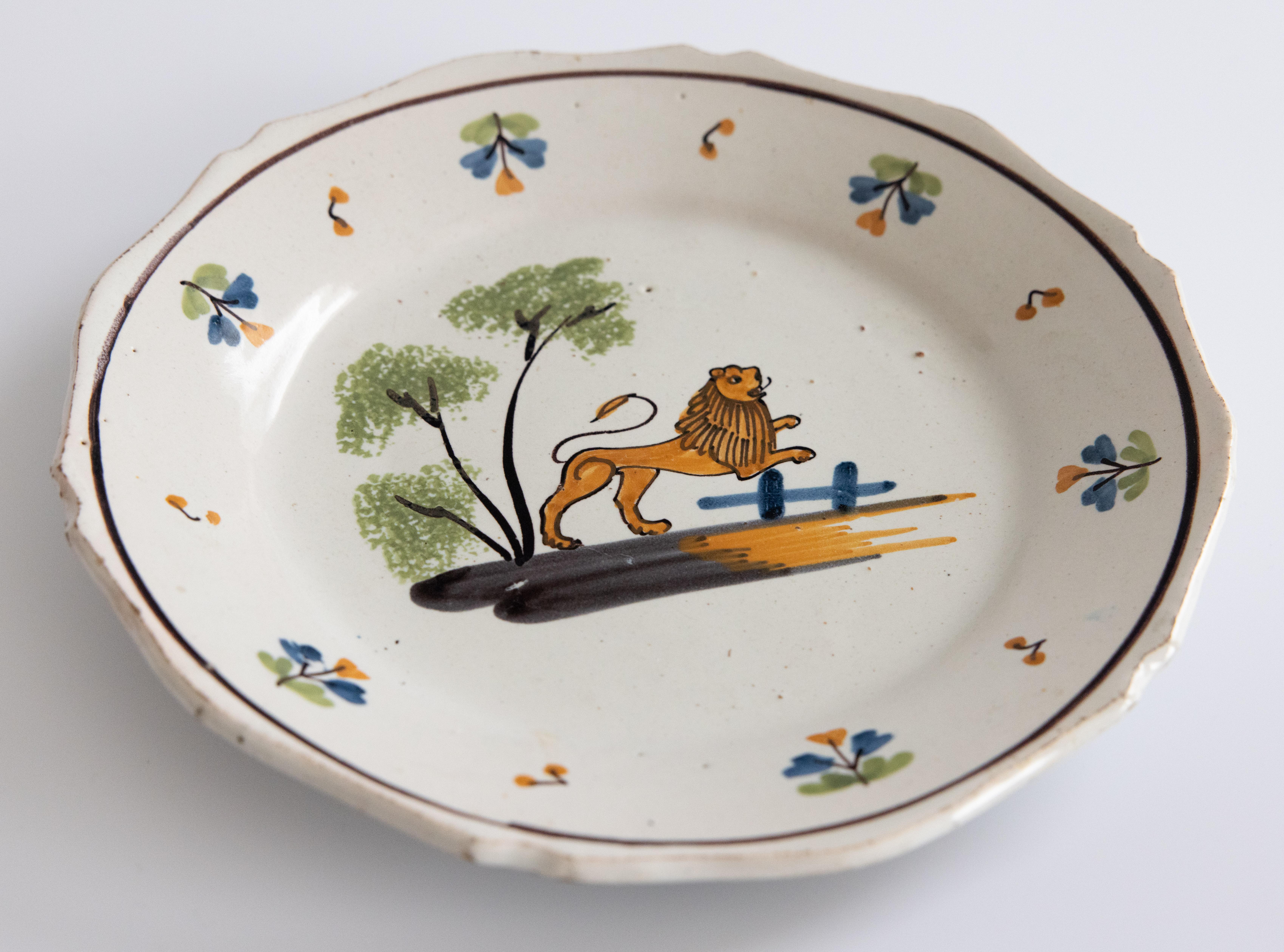 Precioso plato de loza de Nevers del siglo XVIII que representa un león orgulloso, con las patas delanteras levantadas y el borde decorado con flores. 