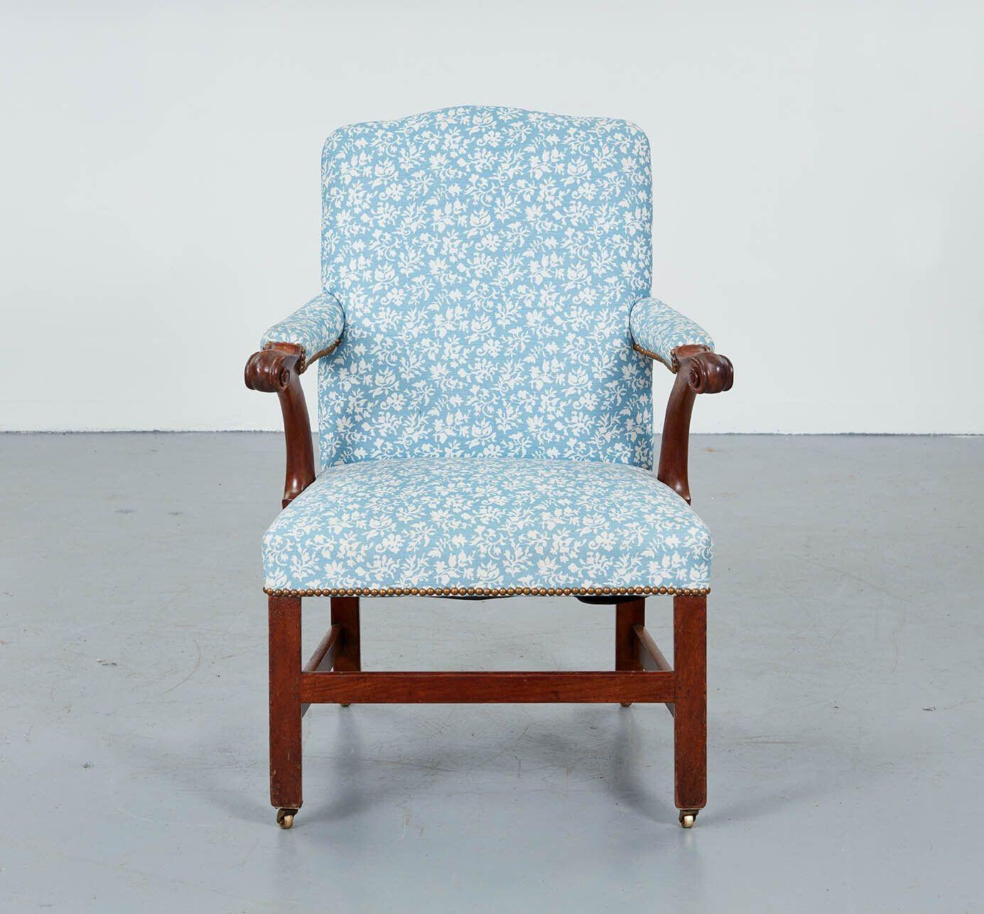 An 18th century armchair with upholstered seat, back and arms and carved hand supports on straight front legs and outswept back legs joined by stretcher on three sides and ending in brass castors.  Upholstered in attractive blue and white Lewis and