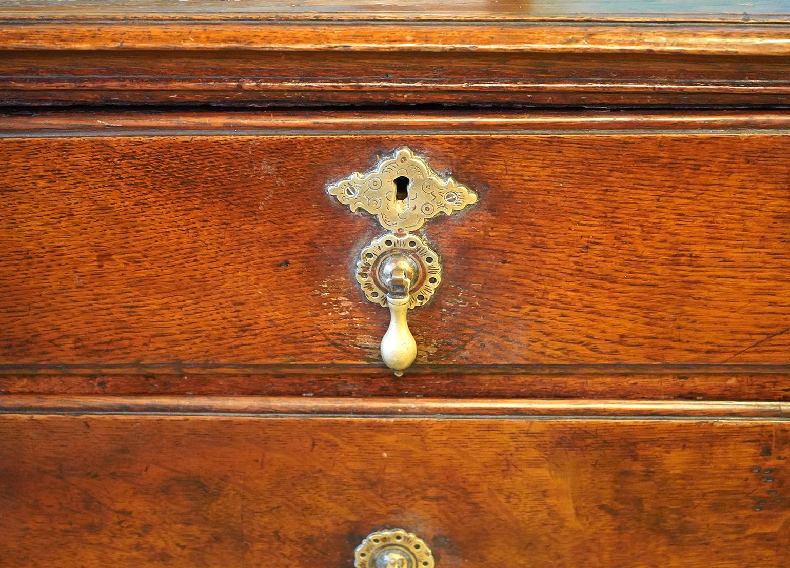 This good and early two part Georgian chest features a two plank top with molded edge above two over three drawers mounted with beautiful brasses. The sides are paneled and resting on rectangular feet in the front with a decorative curve.