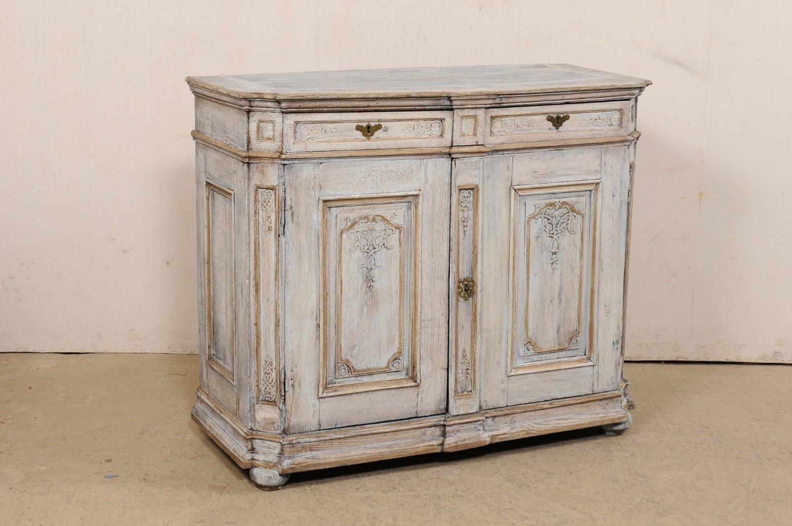 An English carved and painted wood buffet from the 18th century. This antique cabinet from England has been beautifully hand-carved with scroll and foliate designs embellishing the raised panels found along the drawer and door fronts, as well as