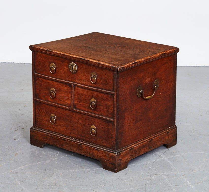 Very good early 18th Century English oak lidded box in the form of a chest of drawers, the hinged top over a configuration of false drawers having half round molded dividers with original ring pulls and pierced escutcheons, standing on original