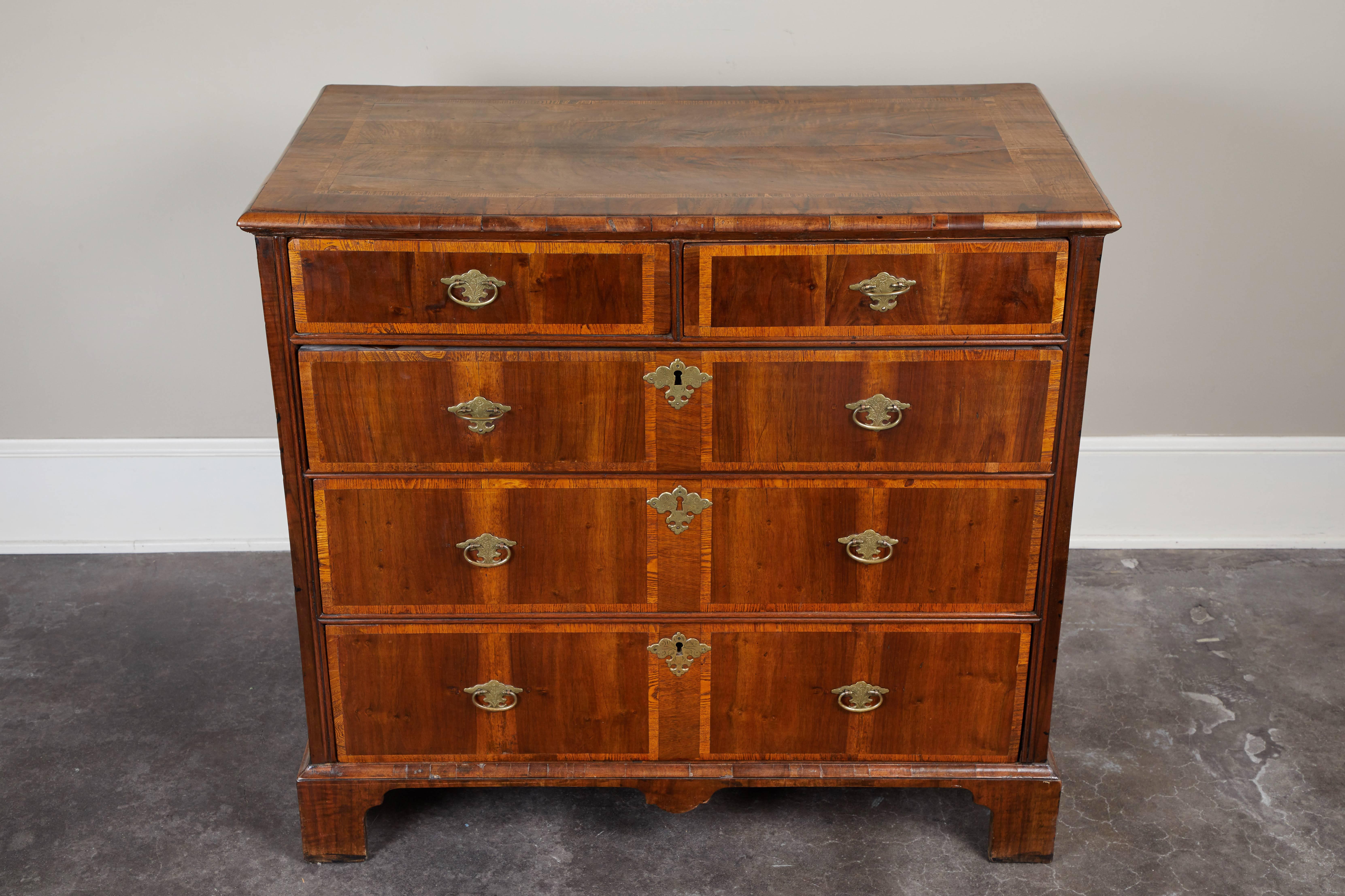 An 18th century George I English walnut chest of drawers. Inlay detailing on the top and face of each of five drawers.