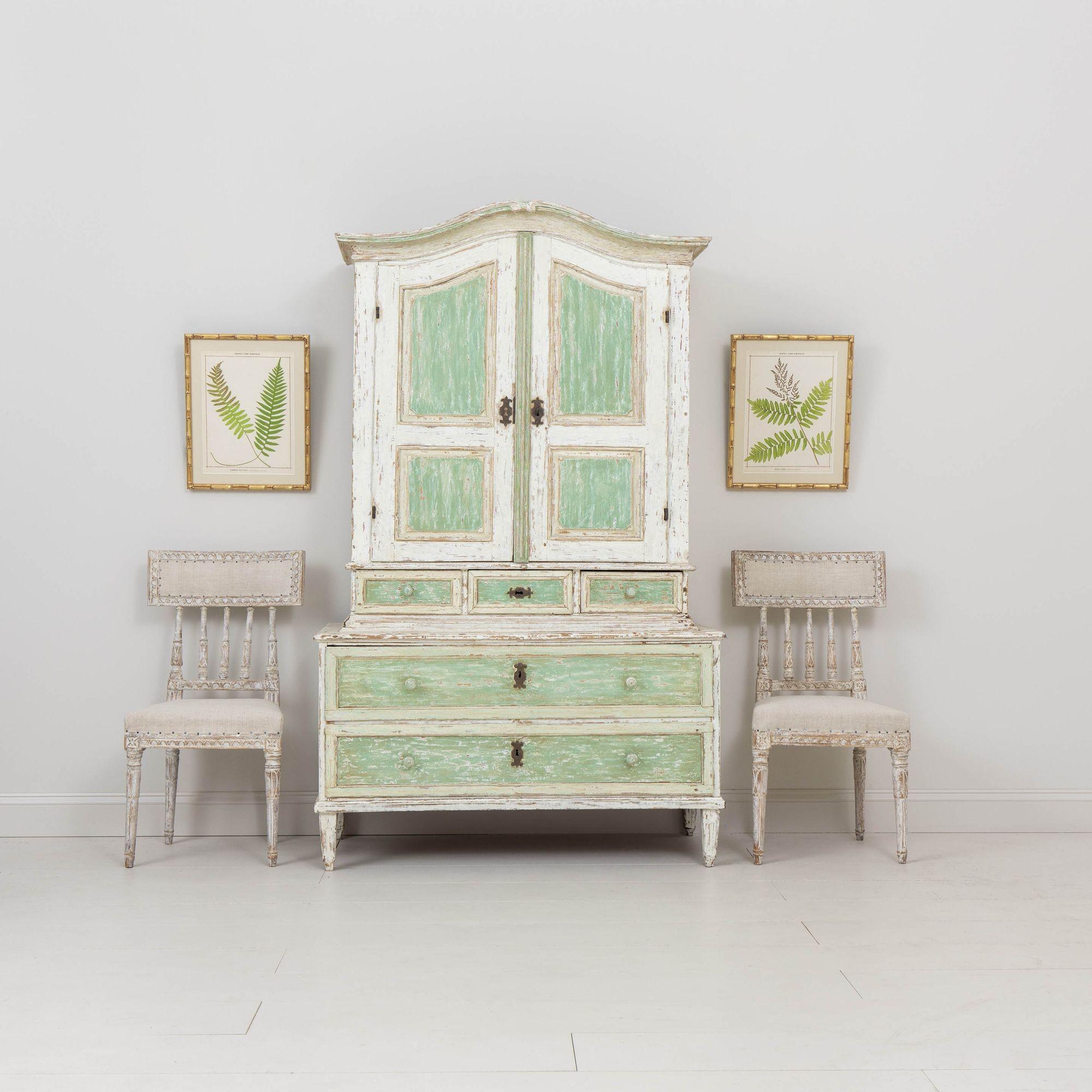 A beautiful two-part cabinet with shaped cornice raised on square tapered legs from the 18th century. This charming cabinet has been hand-scraped to the original green paint. Lovely proportions with plenty of storage space. Circa 1780. The upper
