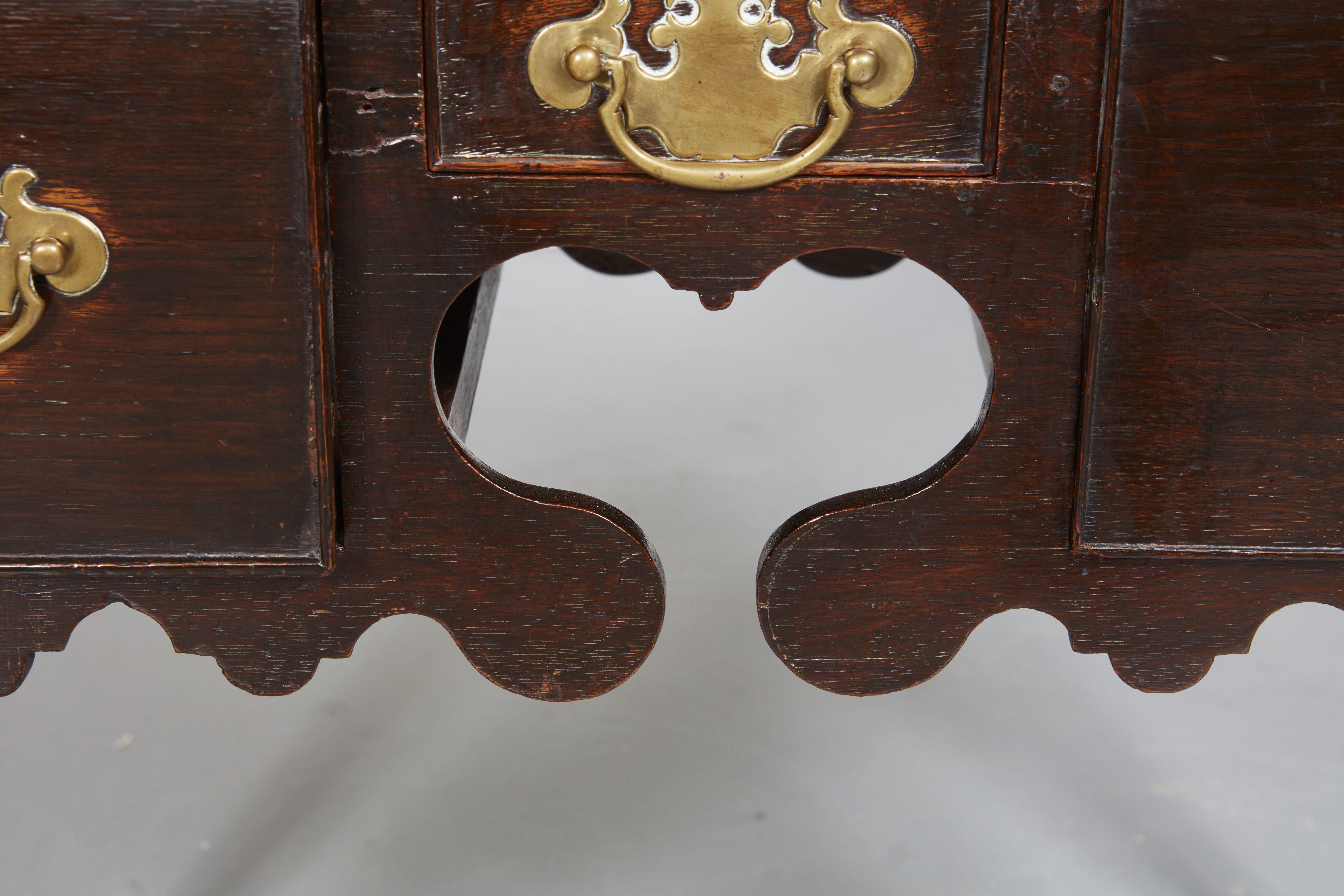 A stunning Folk Art table with sinuous lines standing sprightly on shapely curving legs to front and back, notable for an elaborate apron featuring a heart-shaped silhouette. Three drawers below a top with molded edge with rounded cleft corners.