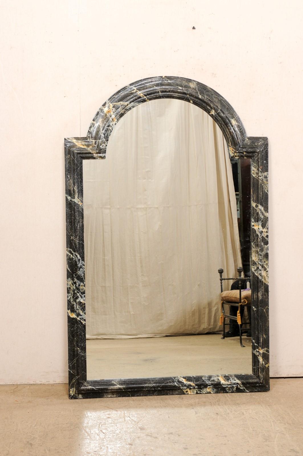 A French carved and faux-marble painted wood mirror from the 18th century. This antique mirror from France has a molded surround with convexly arched top, with straight lines making up the sides and bottom. The wooden frame features one-of-a-kind,