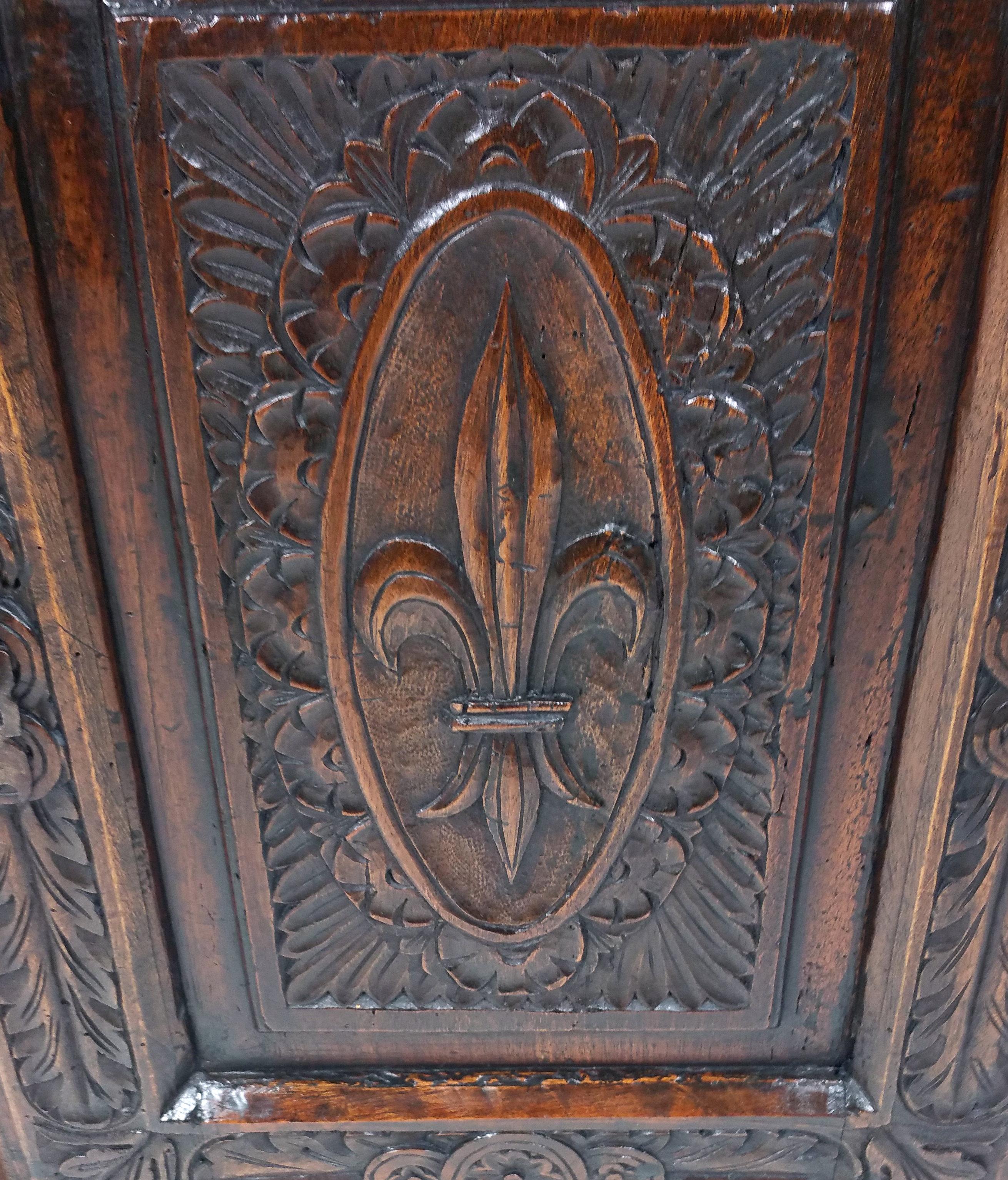 This simplistic yet beautiful 18th century French carved walnut single door side cupboard of small proportions features a profuse carved design decorated with fleur de lis and rosettes, supported on flattened bun feet with the original lock and key.