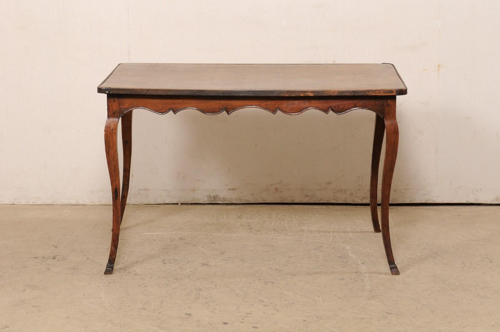 A French carved-wood desk with leather writing pad top from the 18th century. This antique table from France features a rectangular-shaped top with rounded corners and fitted with a warm/camel-colored leather writing pad, which slightly overhangs an