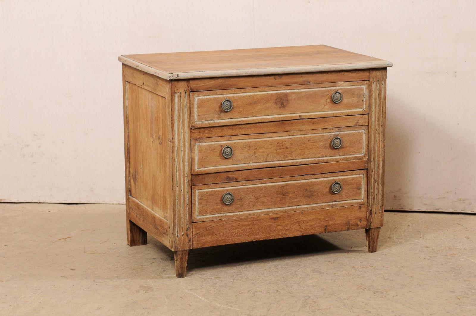 A French wooden three-drawer commode from the 18th century. This antique chest from France is fitted with three graduated drawers which are flanked within fluted front side posts. The skirt is straight and clean. And this chest is raised upon square