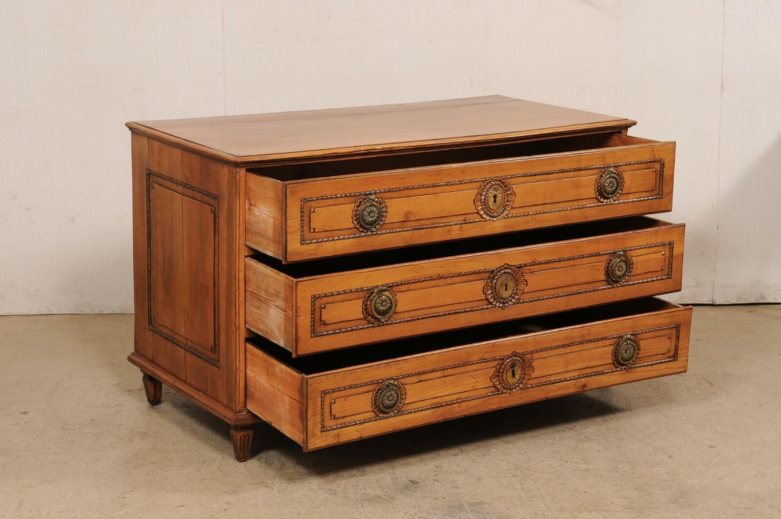 A French wooden three-drawer carved-wood commode from the 18th century. This antique chest from France has a 4.5 foot long rectangular-shaped top, over case which houses three full-sized and graduated drawers. The skirt is straight and clean, and