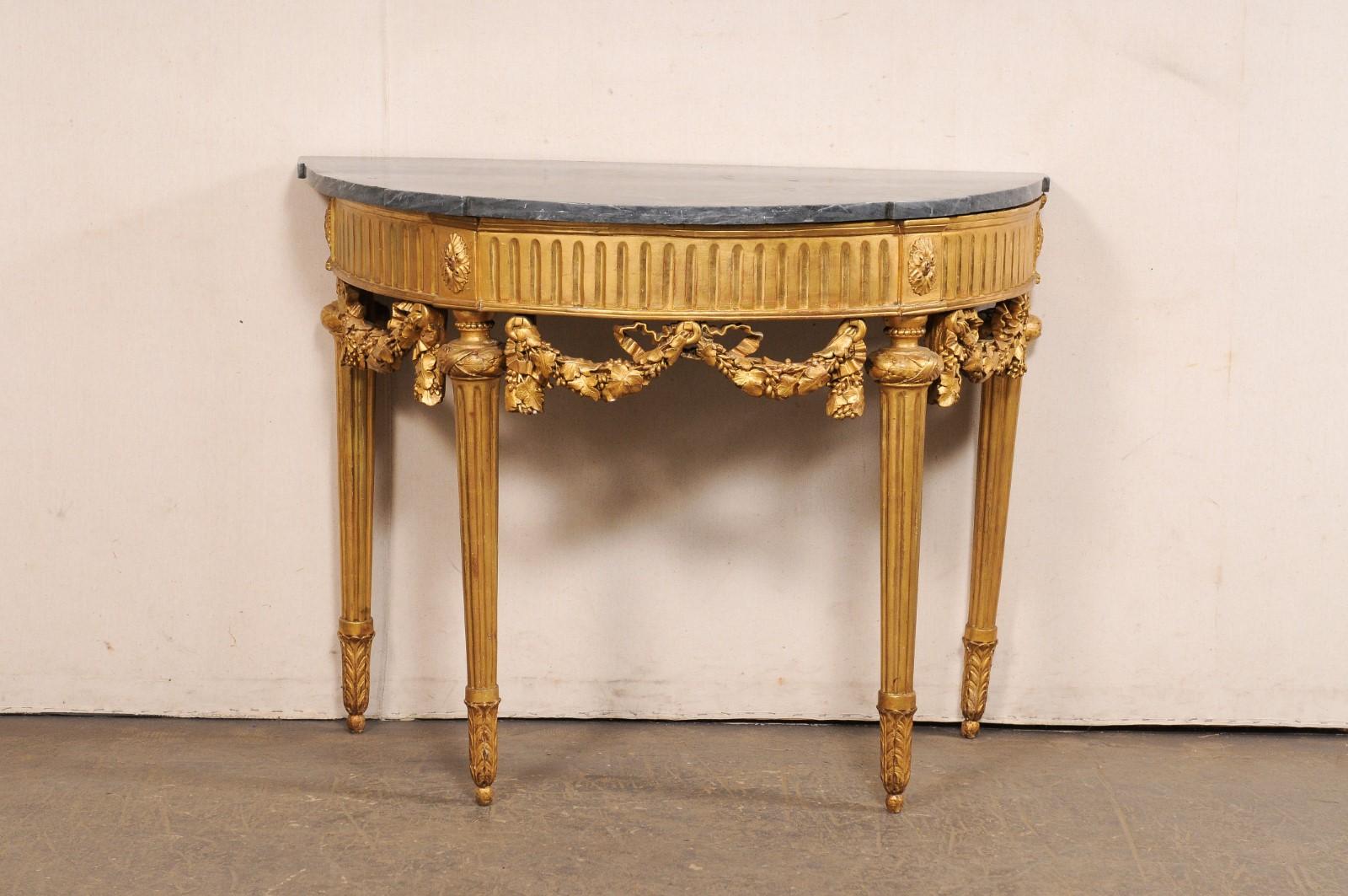 Table française en demi-lune, avec une jupe délicatement sculptée et un plateau en marbre bleu turquin, du XVIIIe siècle. Cette table console ancienne de France présente un plateau de marbre en forme de demi-lune (avec des saillies rectangulaires