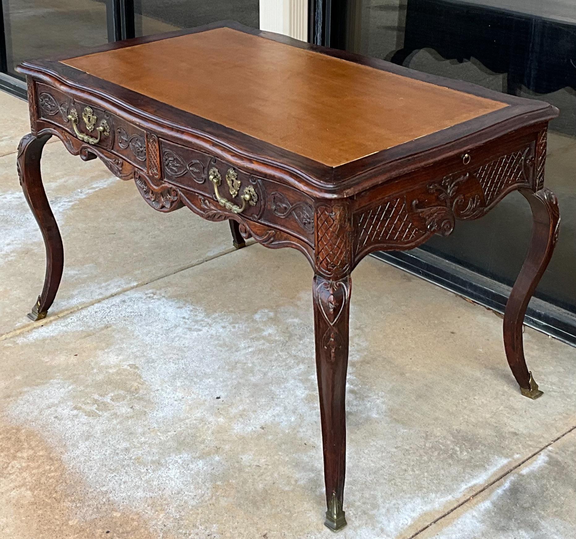 This is a special piece! It is a late 18th century carved oak and gilt bronze writing desk. It has two drawers and two identical faux drawers. Each foot is capped in bronze. The felt lined drawers have dovetail construction. The gold tooled leather
