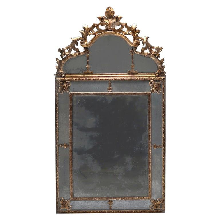 A classic Louis XIV period mirror in the manner of Jean Bérain. Original mercury mirror plates, naturally aged to a soft pewter tone, still retaining its beautiful reflective quality. Carved pediment with leaf motif, marginal glass borders of