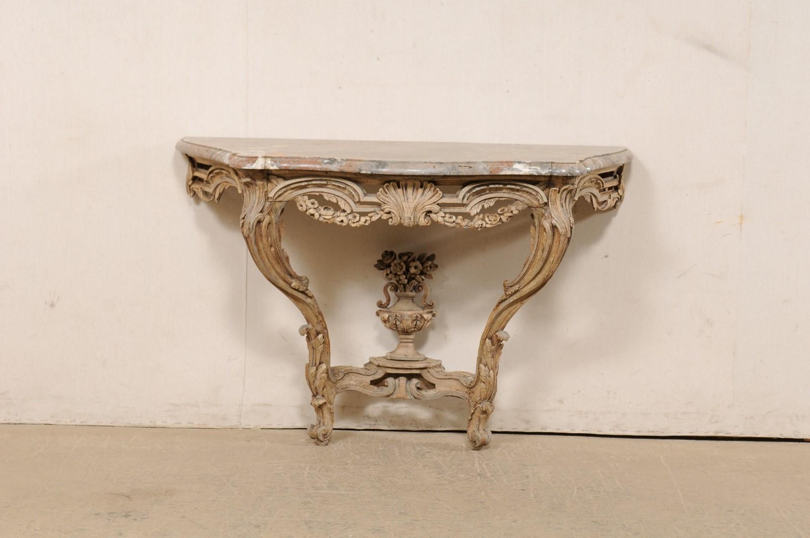 A French neoclassical beautifully-carved wood wall console, with original serpentine marble top, from the 18th century. This period Neoclassic table from France has a shapely serpentine marble top with flattened backside which is raised upon a wood