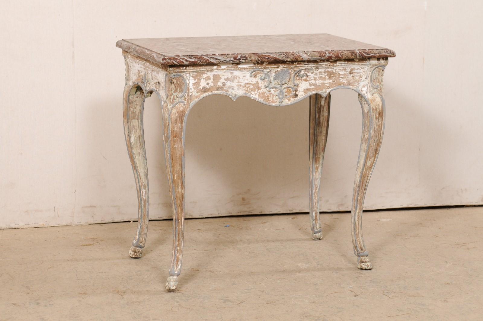 A French smaller-sized console table, with its original marble top, from the 18th century. This antique table from France features its original marble top, in beautiful hues of merlot and gray, supported atop a carved wood base with scalloped