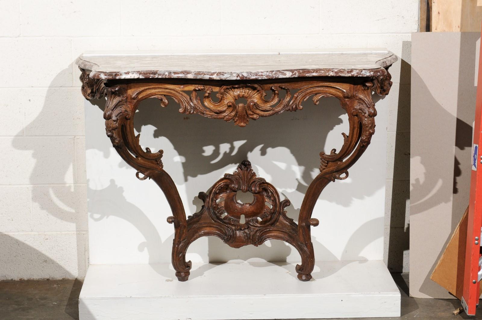 An 18th Century French Regence Period Oak Wall Mounted Console with Rouge Royale Marble Top. The base is solid and features beautifully carved oak foliage featuring symmetrical acanthus leaf, scrollwork and a hooked foot. Rouge Royal is a beautiful