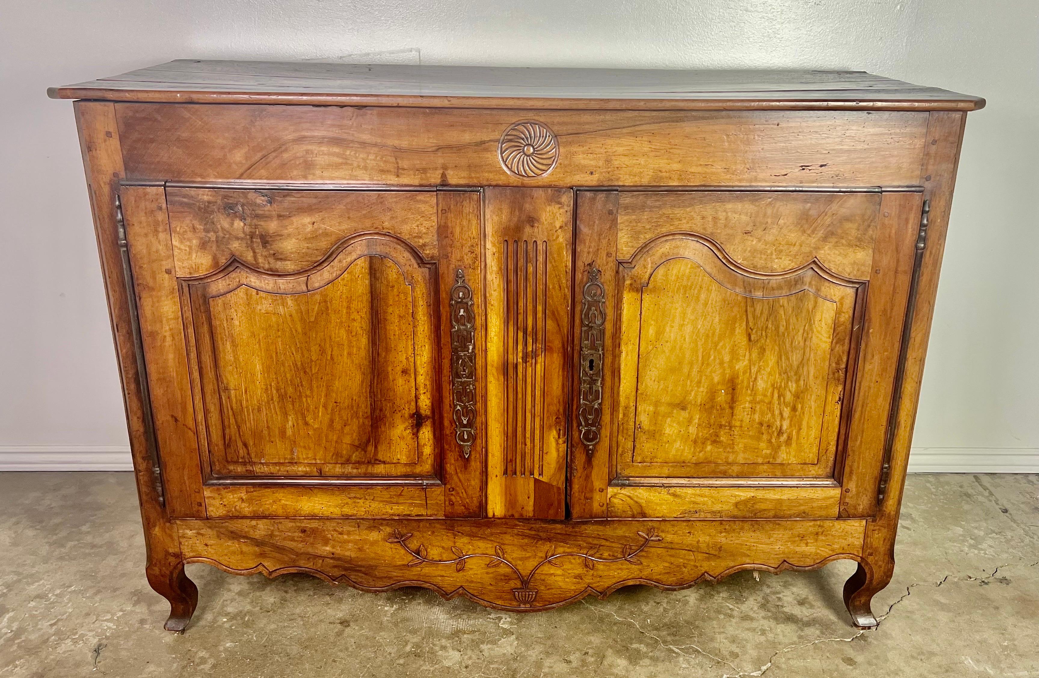 18th century French walnut buffet. The buffet has two paneled doors with original brass hardware. The body of the piece stands on four cabriole legs. The designs on both the bottom and top are simple and elegant. The walnut has developed a beautiful