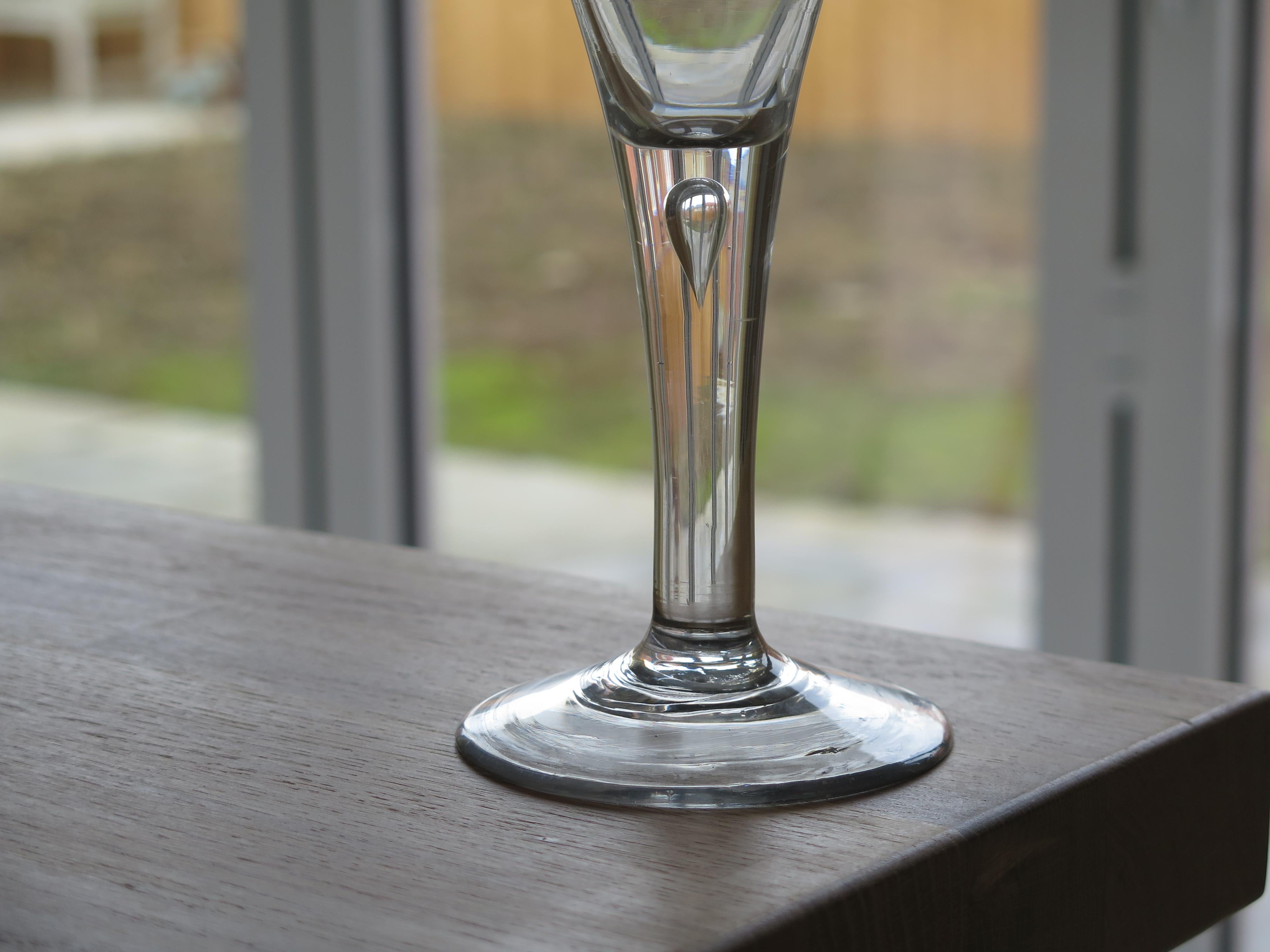 This is a very good, tall, English George 11nd period, hand blown wine drinking glass, dating to the George II period of the mid-18th century, circa 1750.

These 18th century hand blown drinking glasses are uniquely individual and very