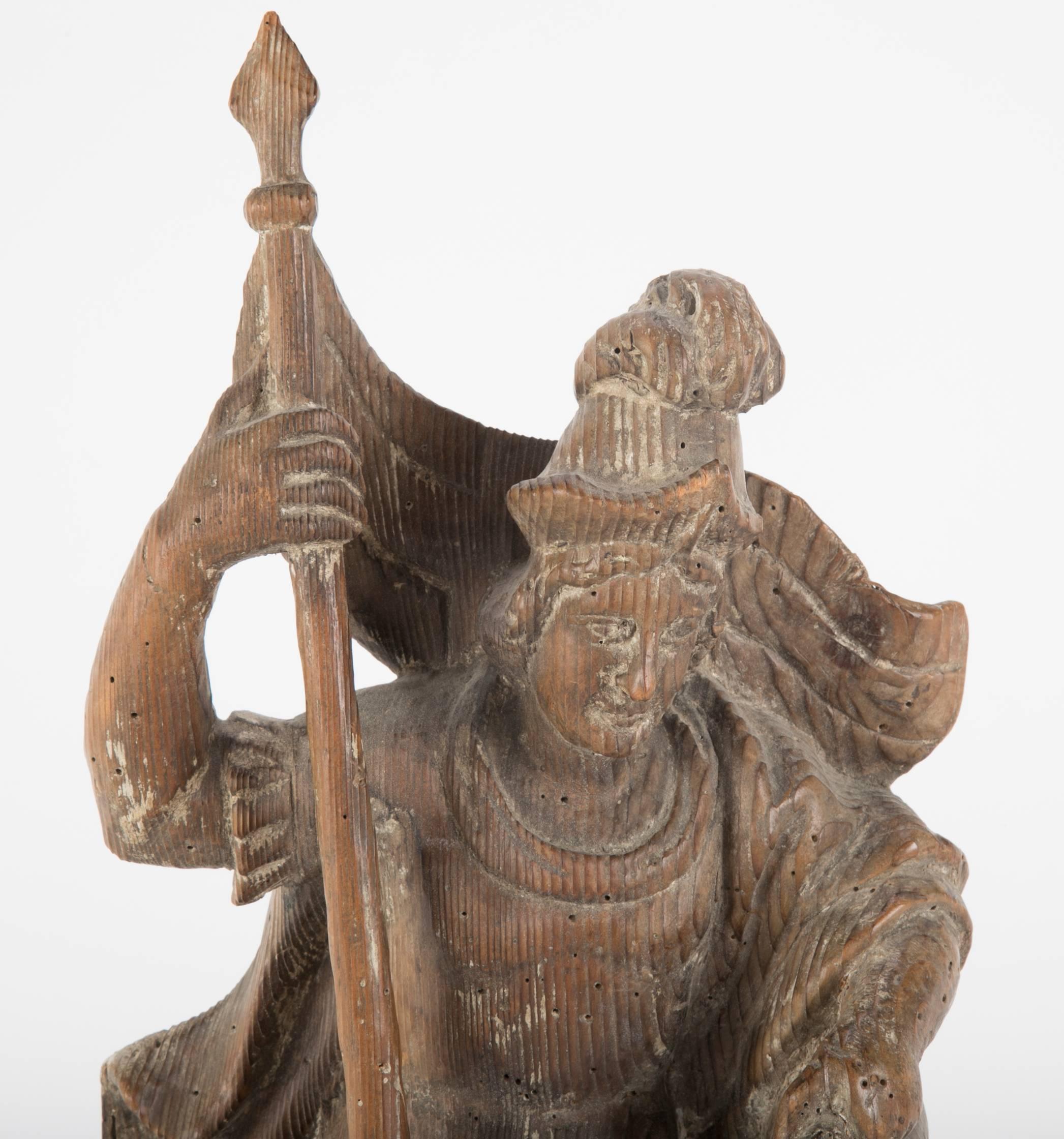 Pine carving of Saint Florian, the patron saint of fire fighters, 18th century German, the saint shown holding a staff with a banner in one hand, pouring a bucket of water over a burning bilding with the other. With an old label of Ludwig Roger, a