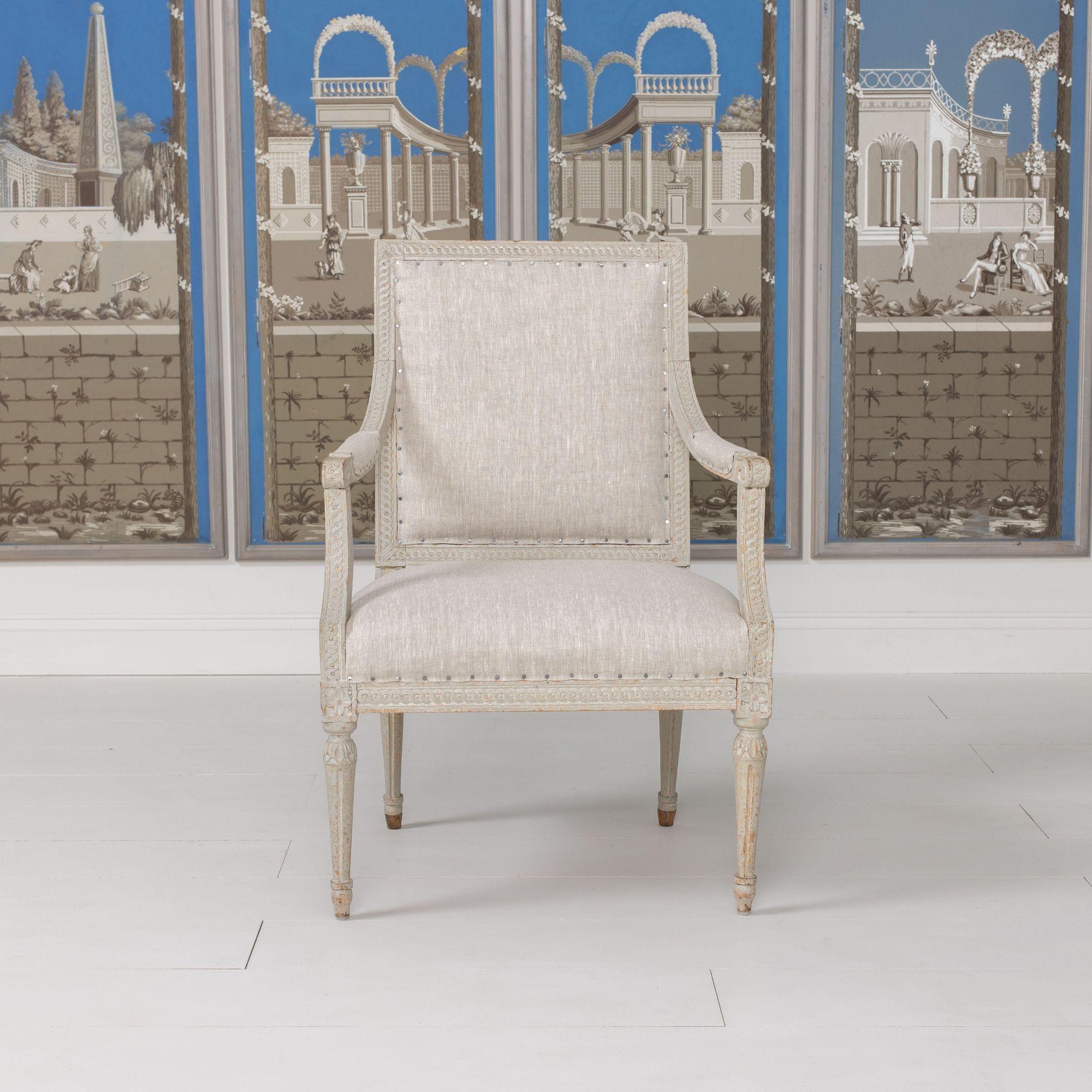 A beautiful 18th c. Louis XVI period armchair from northern Germany made of beech wood, hand scraped to the original paint and newly upholstered in linen fabric with nail head trim. Circa 1770. Beautiful guilloché carved detail on the back and seat