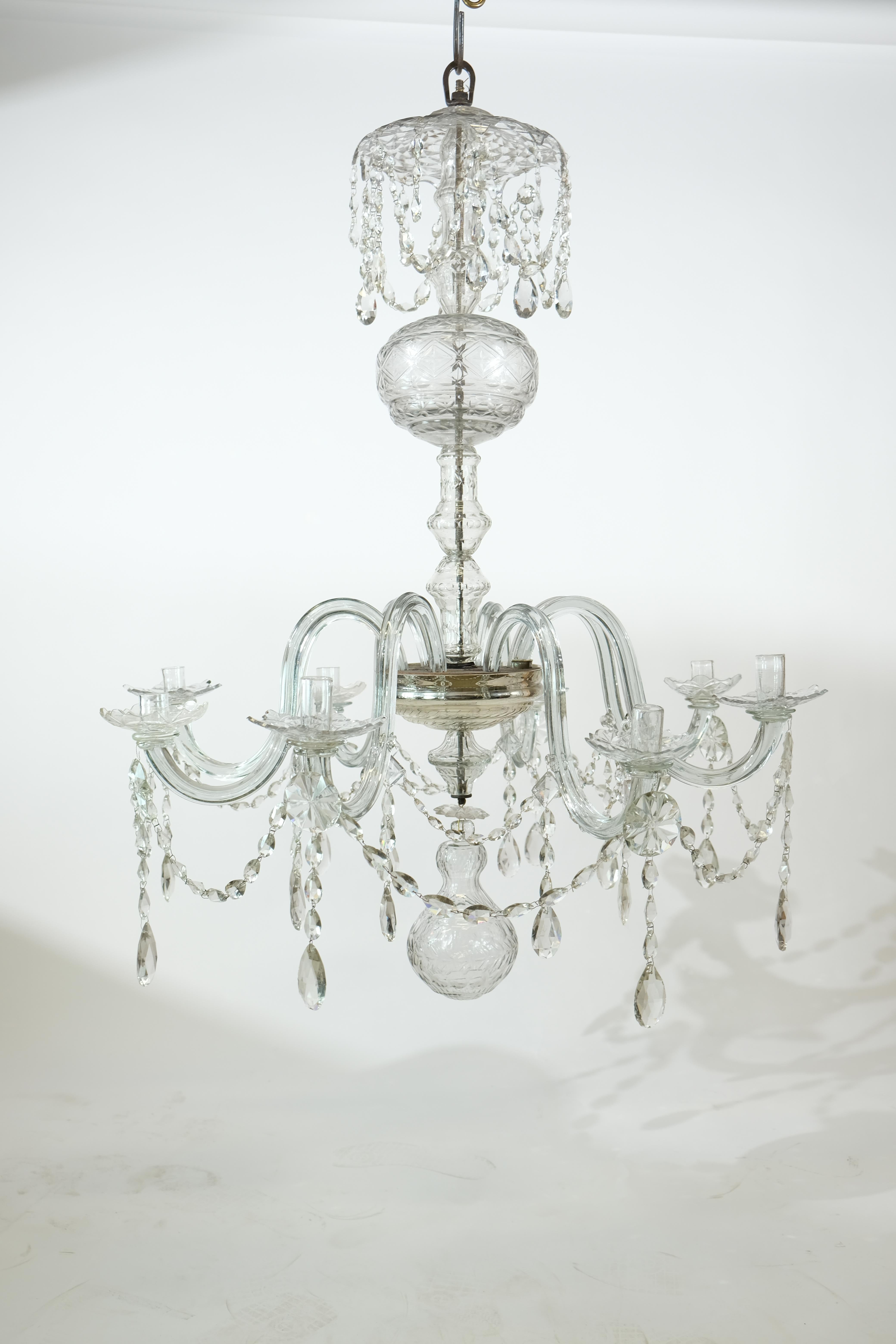 A large high quality 18th c chandelier. Most probably English. It has eight arms of glass that holds the candleholders. The central part is made up by several cut glass bulbs and bottles. The quality of the cut crystal is very high. On top of the