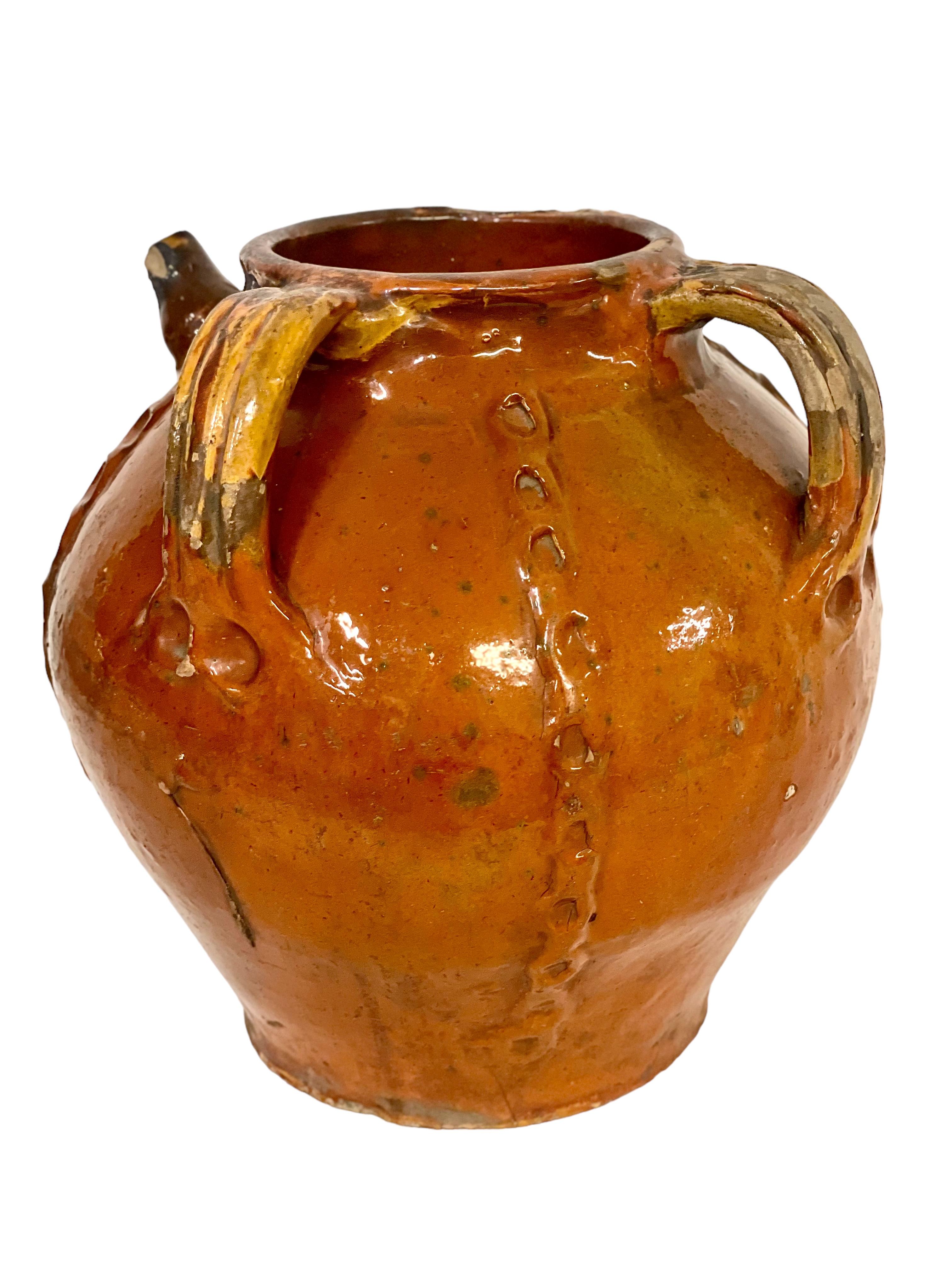 A rustic and very attractive antique French walnut oil jug, with three handles and a shaped pouring spout. Glazed all over in a gorgeous glossy caramel-coloured glaze, this gently rounded vessel has been further embellished with four applied and