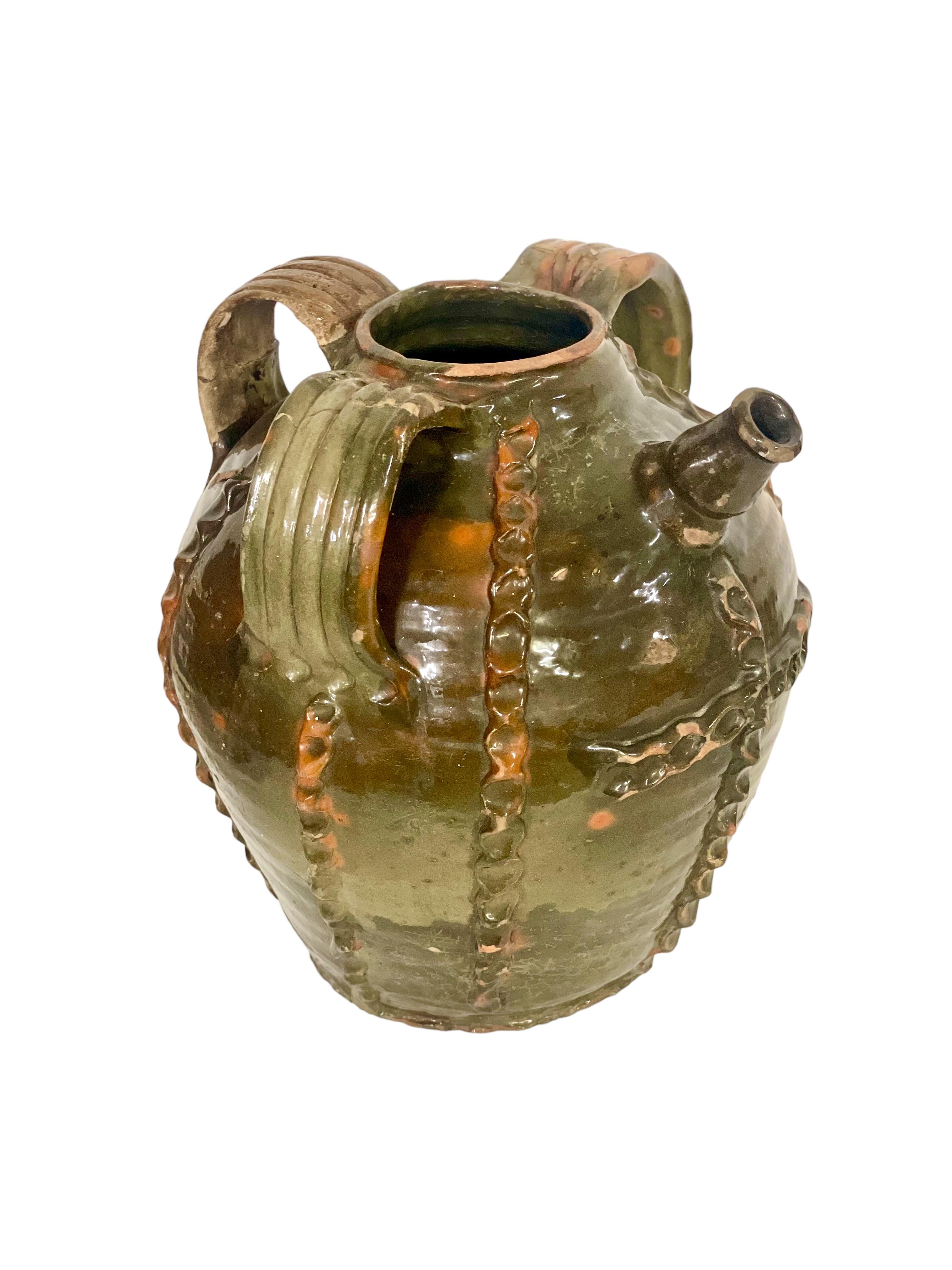 This is a fabulous example of a large 18th century French walnut oil jar, with three decorative handles and short pouring spout. Retaining its original dusky-green glaze, the jar is embellished with vertical strips in an exceptionally decorative