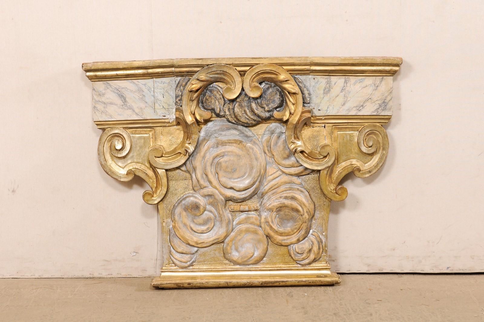 An Italian carved and gilt wood wall plaque from the 18th century. This antique wall ornament from Italy is a nicely sized piece at roughly four feet in width and just shy of three feet tall. It has a thick T-shaped figure adorn with carved roses,