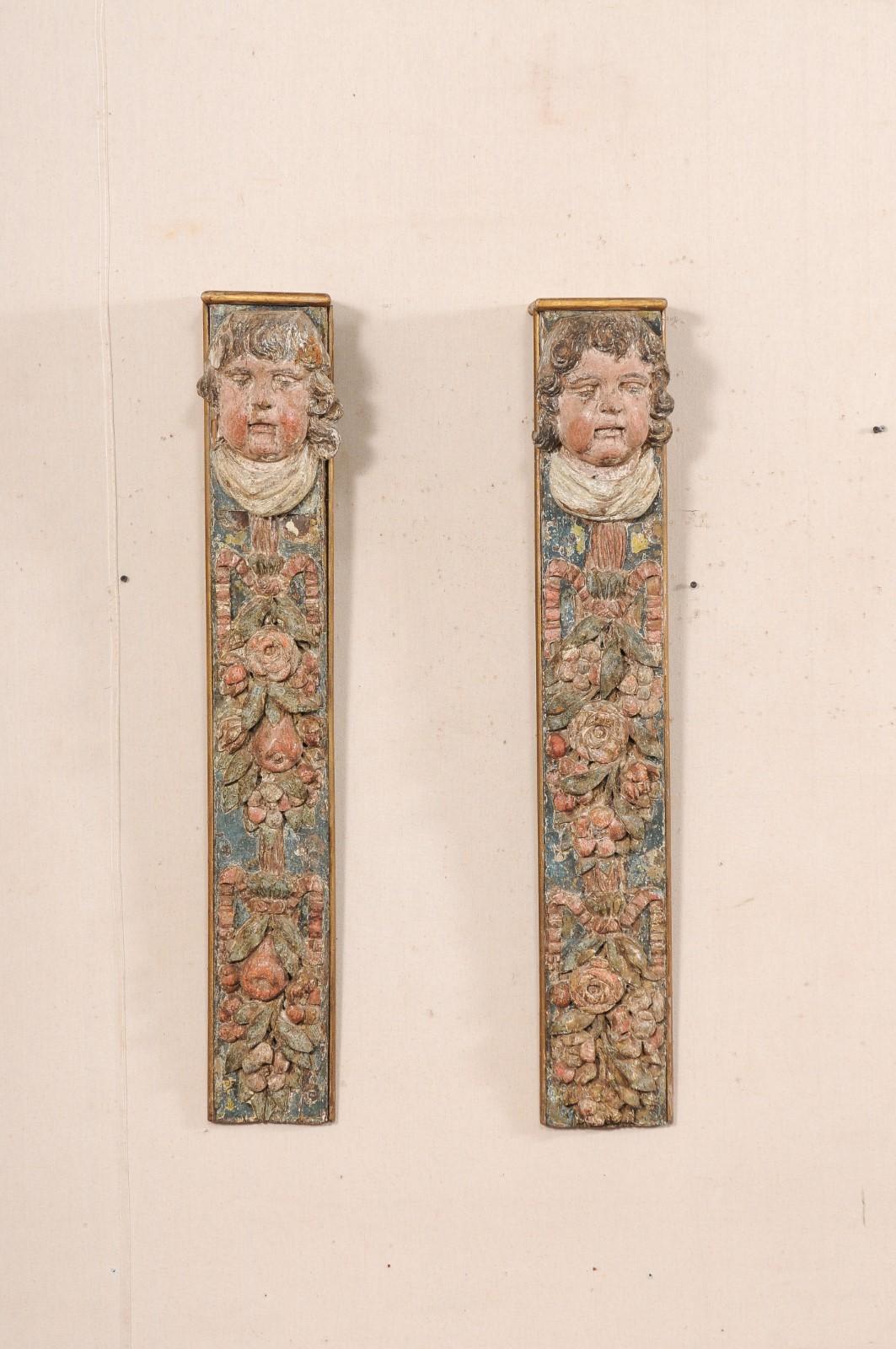 Paire de consoles murales baroques italiennes en bois sculpté et peint du XVIIIe siècle. Ces supports muraux décoratifs anciens d'Italie présentent chacun une tête de putto sculptée au sommet, surmontant un motif en cascade de rubans, de fleurs et