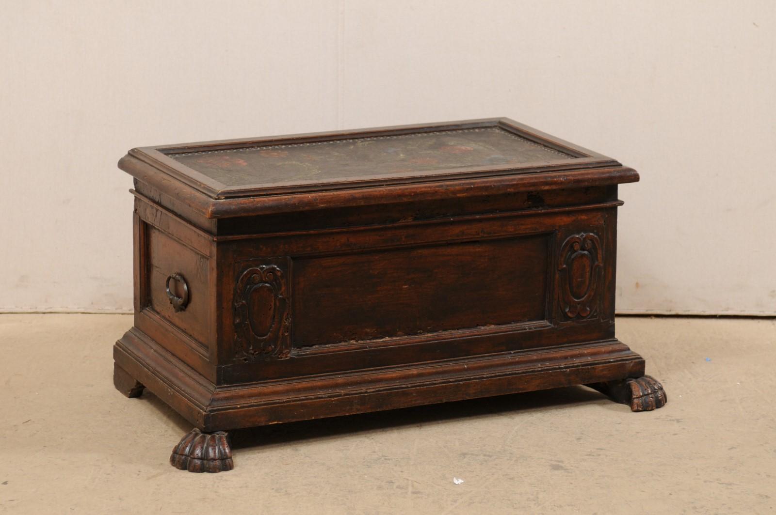 An Italian trunk with hand painted leather top from the 18th century. This antique cassone from Italy features a recessed panel top with leather painted in a floral motif adorning the top. The front has a rectangular recessed panel flanked within a