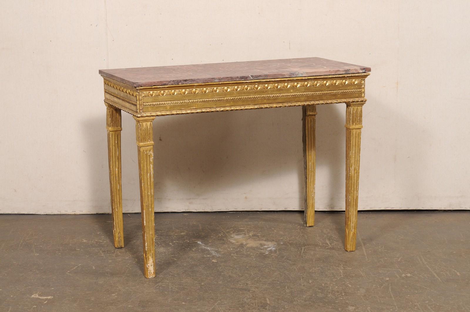 Consolle italiana in legno intagliato e dorato con piano in marmo, del XVIII secolo. Questo tavolo antico italiano ha un piano in marmo di forma rettangolare, che poggia su un grembiule rettangolare ornato da dettagli di rifinitura ben intagliati.