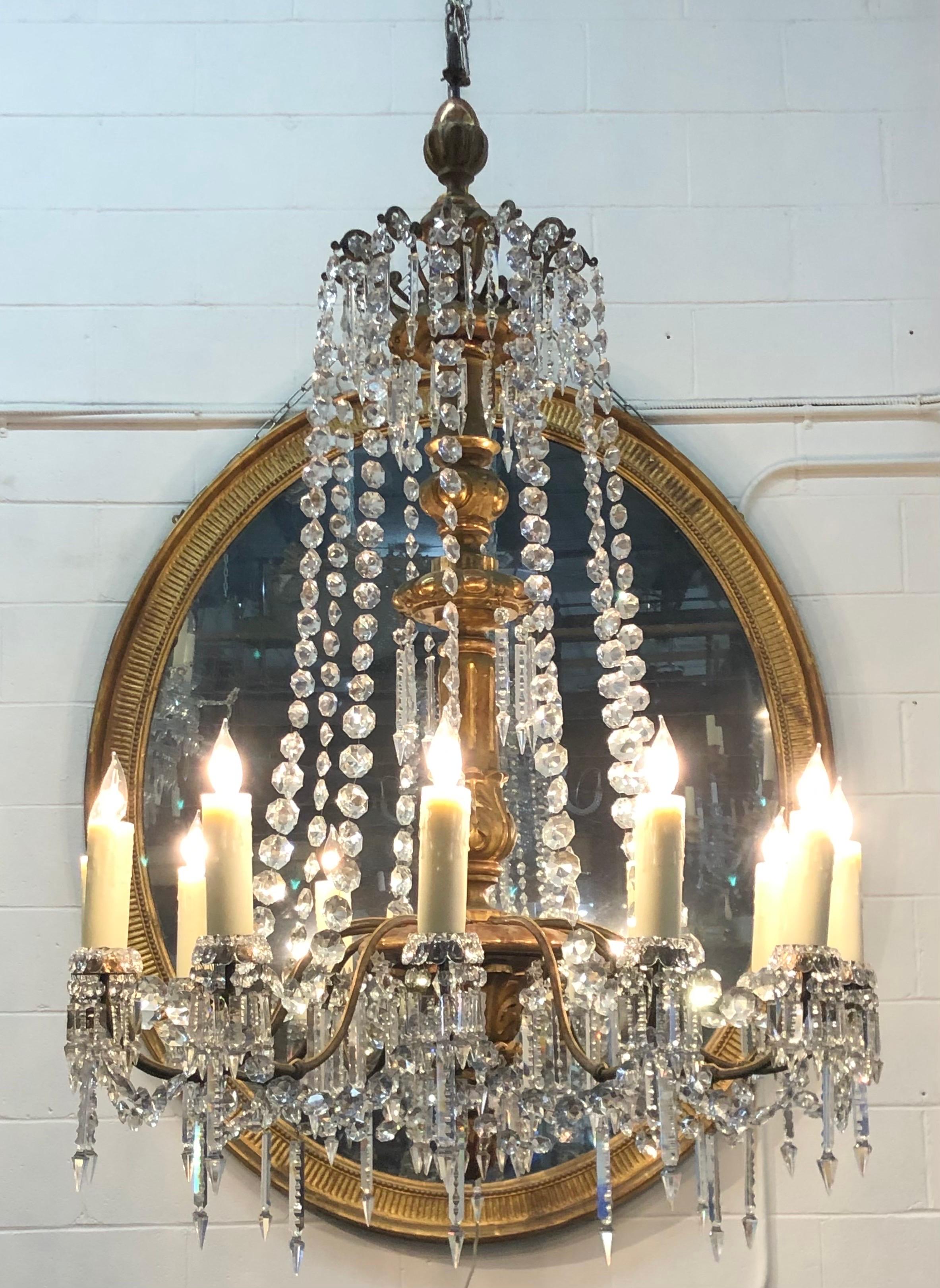 This Regal Monumental Louis XVI Period Giltwood, Bronze-Lacquer, Tôle, Wrought Iron & Crystal Chandelier was made in Italy in the 18th century. The elegant hand-carved Giltwood and Bronze-Lacquered Foliate Stem is carved with rings, fluting,