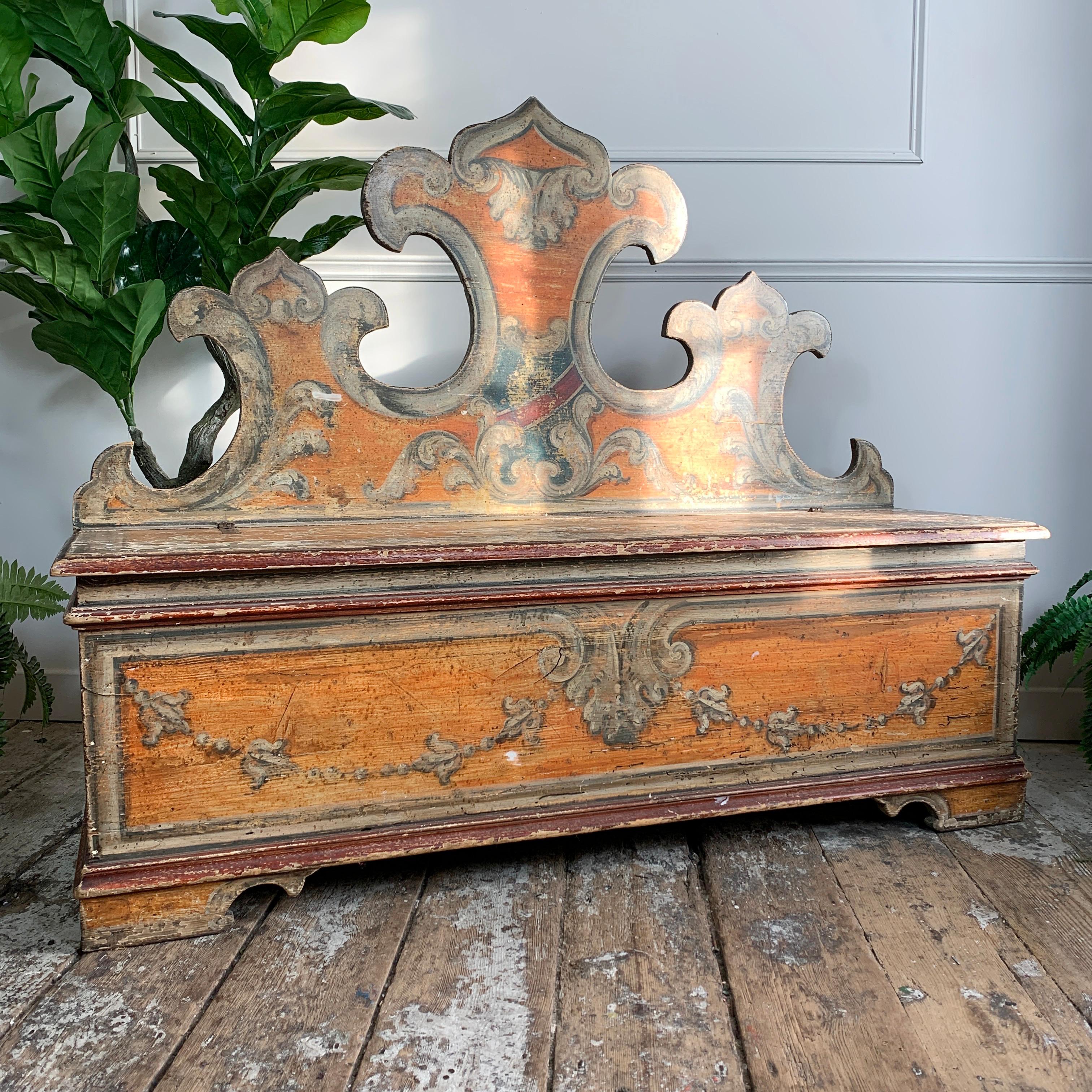 A wonderful 18th century Italian Cassapanca, the tall back is carved as Florentine fleur de lis, and the seat and back have hand painted decoration, depicting more fleur de lis, acanthus leaves, tromp l'oeil and the crest of the Florentine family