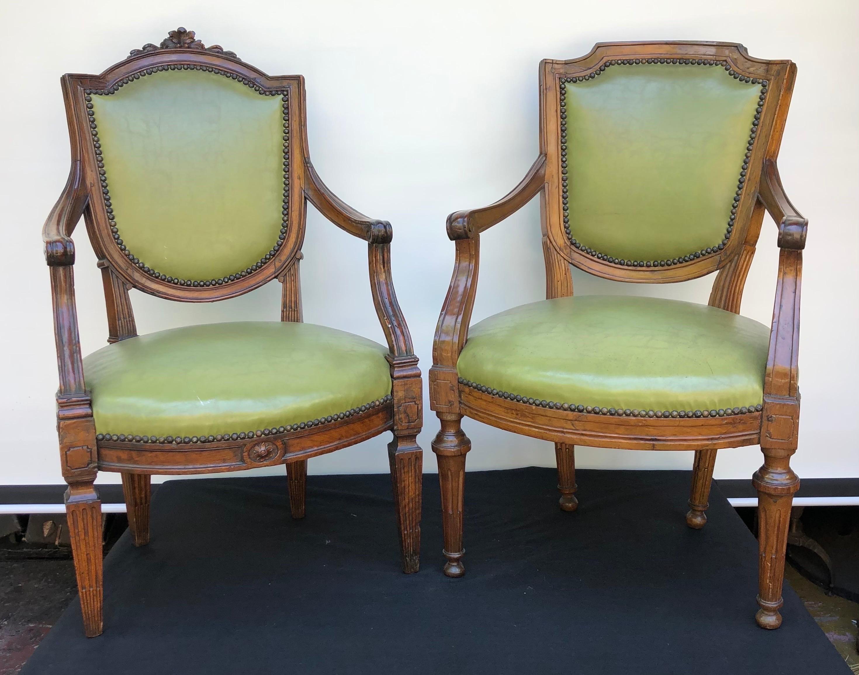 Two 18th Century complementary Italian Walnut Neoclassical Arm Chairs with magnificent green leather upholstery. The two Walnut Arm Chairs are mortise and tenon through with pegs. These Italian Chairs would work well in an Office, Library, or Bar.