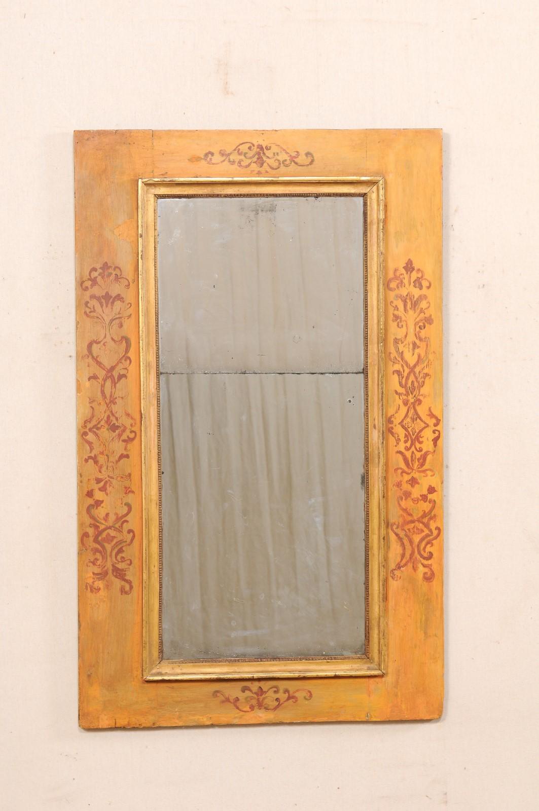 An Italian decoratively hand-painted wall mirror from the 18th century. This antique mirror from Italy has thick wood surround that has been hand-painted with foliate ornamentation about the central sections of each of the four sides. There is a